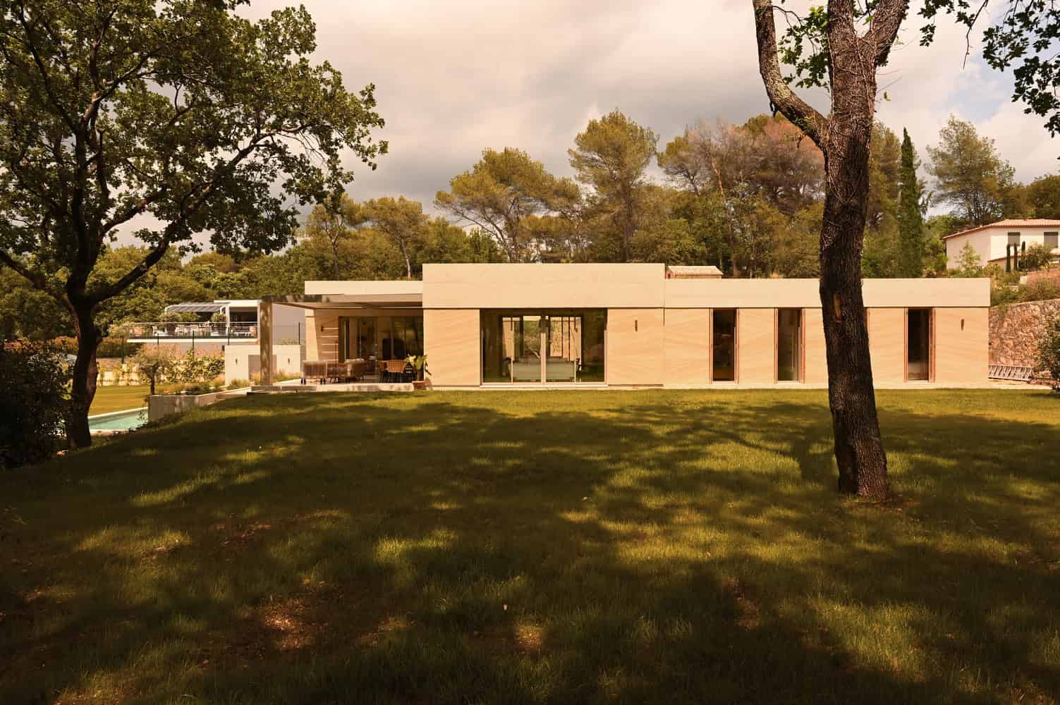 Contemporary modern house with clean lines and large glass windows nestled in lush green landscape, showcasing innovative architecture and stylish outdoor living spaces.