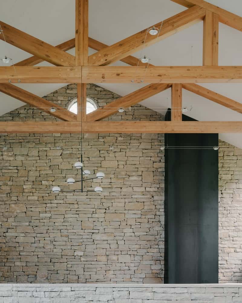 Living Room Warmth Living room with timber ceiling, stone accent wall, and panoramic glazing to the landscape.