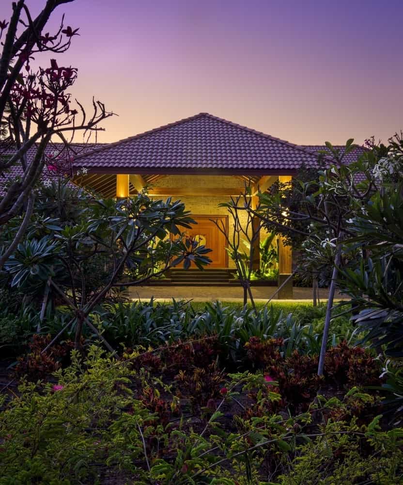 Living to Court Living space opening to a green court with stone plinths and timber ceiling.
