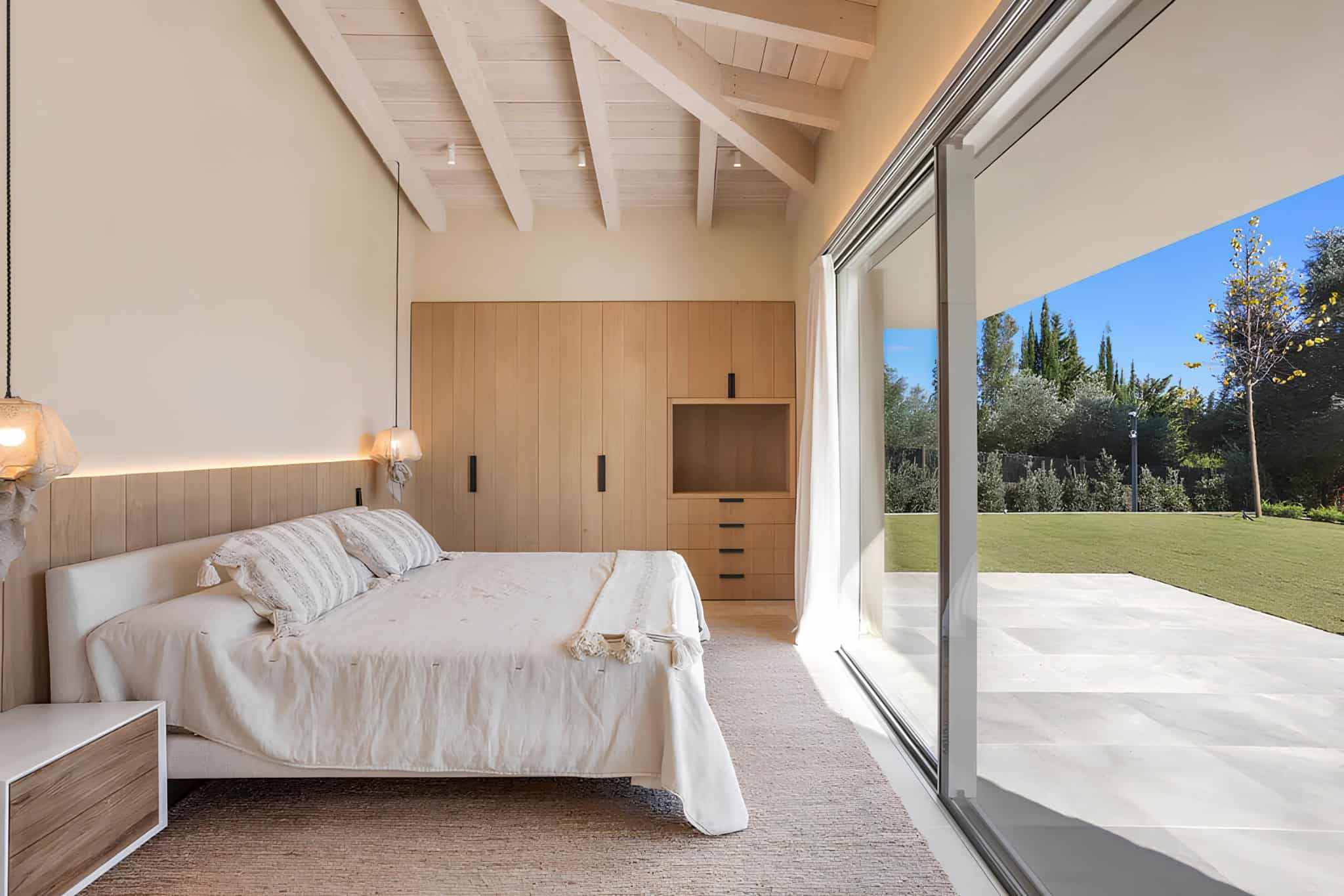 Mediterranean Style Bedroom Natural Light Wood Minimal Mediterranean bedroom with wood accents and full-height sliding glass doors.