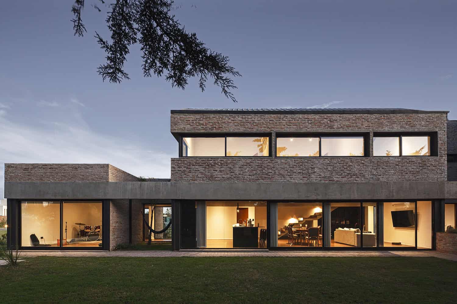 Modern brick and concrete residential house with large floor-to-ceiling windows showcasing contemporary architecture and stylish interior design.