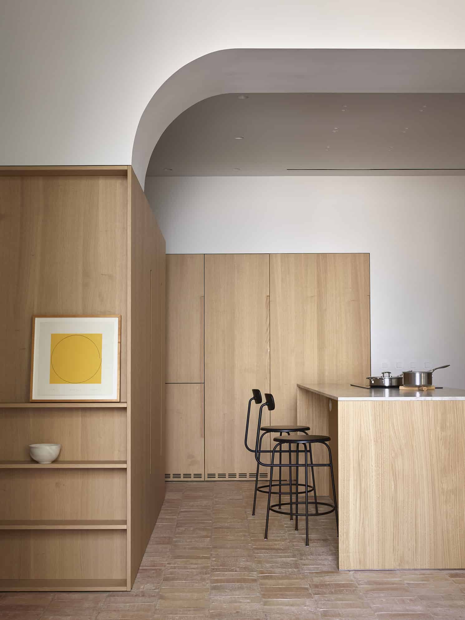 Modern minimalistic kitchen with light wood cabinetry and black barstools, featuring clean lines and contemporary design elements, perfect for stylish urban interiors.