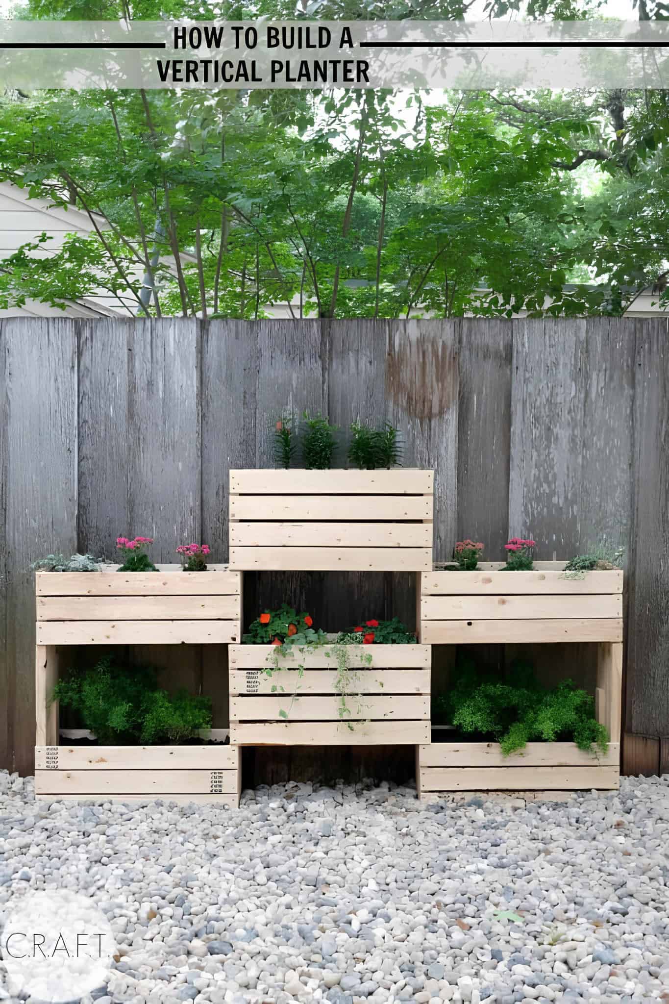 Tiered wooden crate planter with herbs against a fence