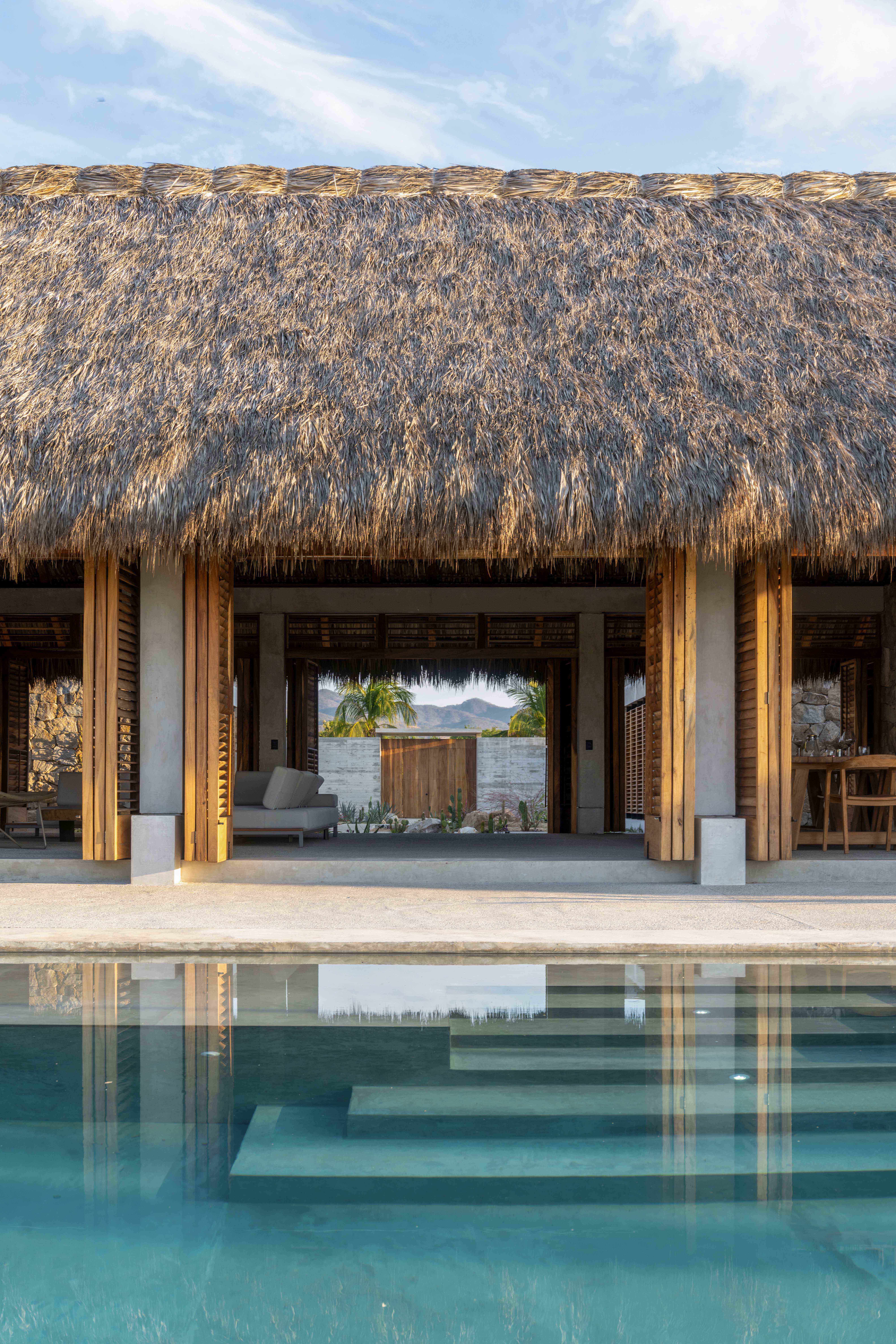 Tate House / MATERIA / Mexico Exquisite tropical villa with thatched roof, open-concept living space, and swimming pool, showcasing modern architecture blended with natural materials for luxury and relaxation.