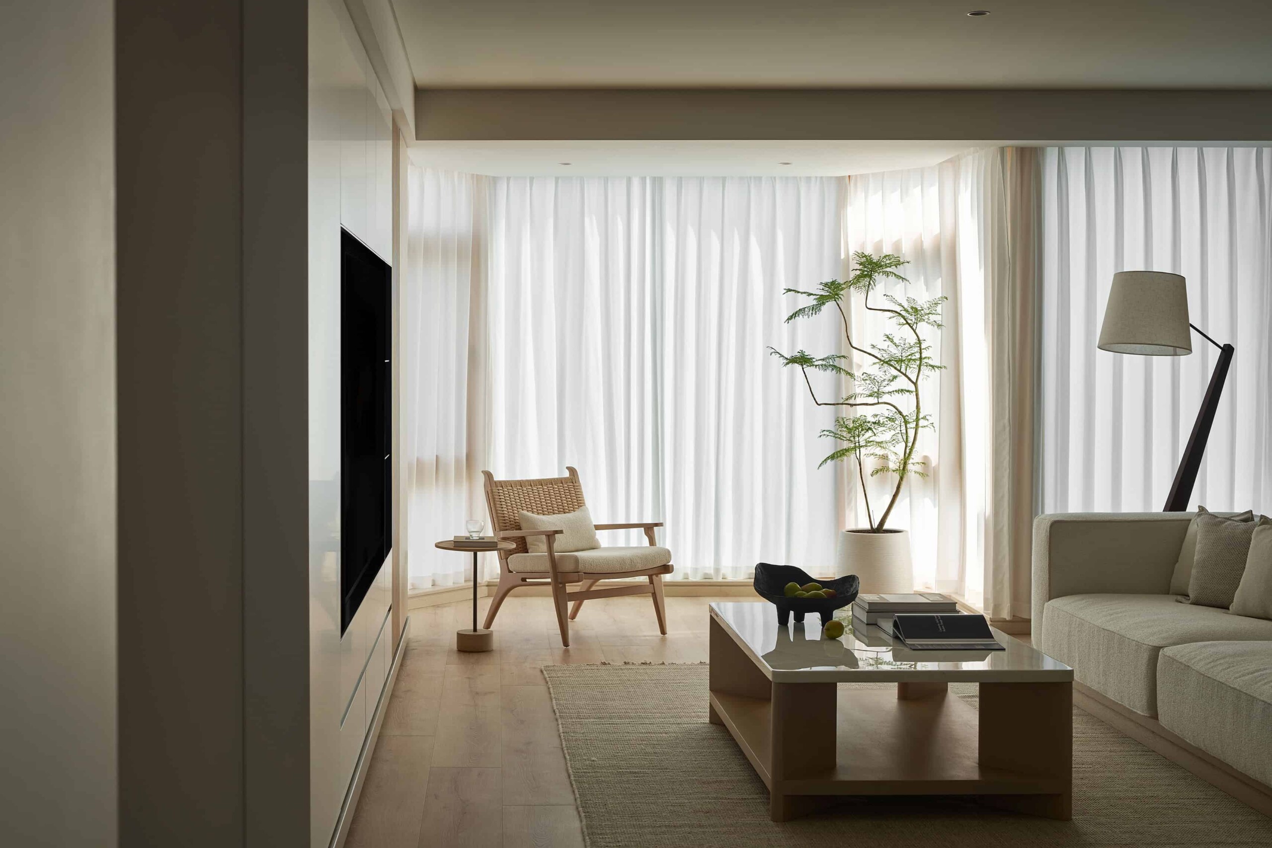Modern minimalist living room with neutral tones, large windows with white curtains, and stylish furniture. Bright and airy interior design emphasizing natural light and contemporary decor.