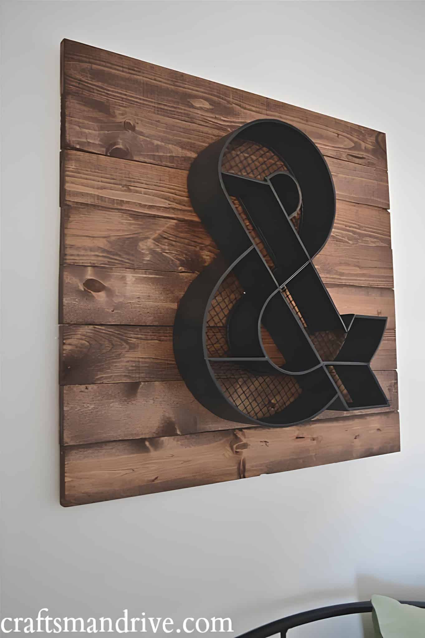Modern industrial ampersand symbol mounted on stained wood slats.