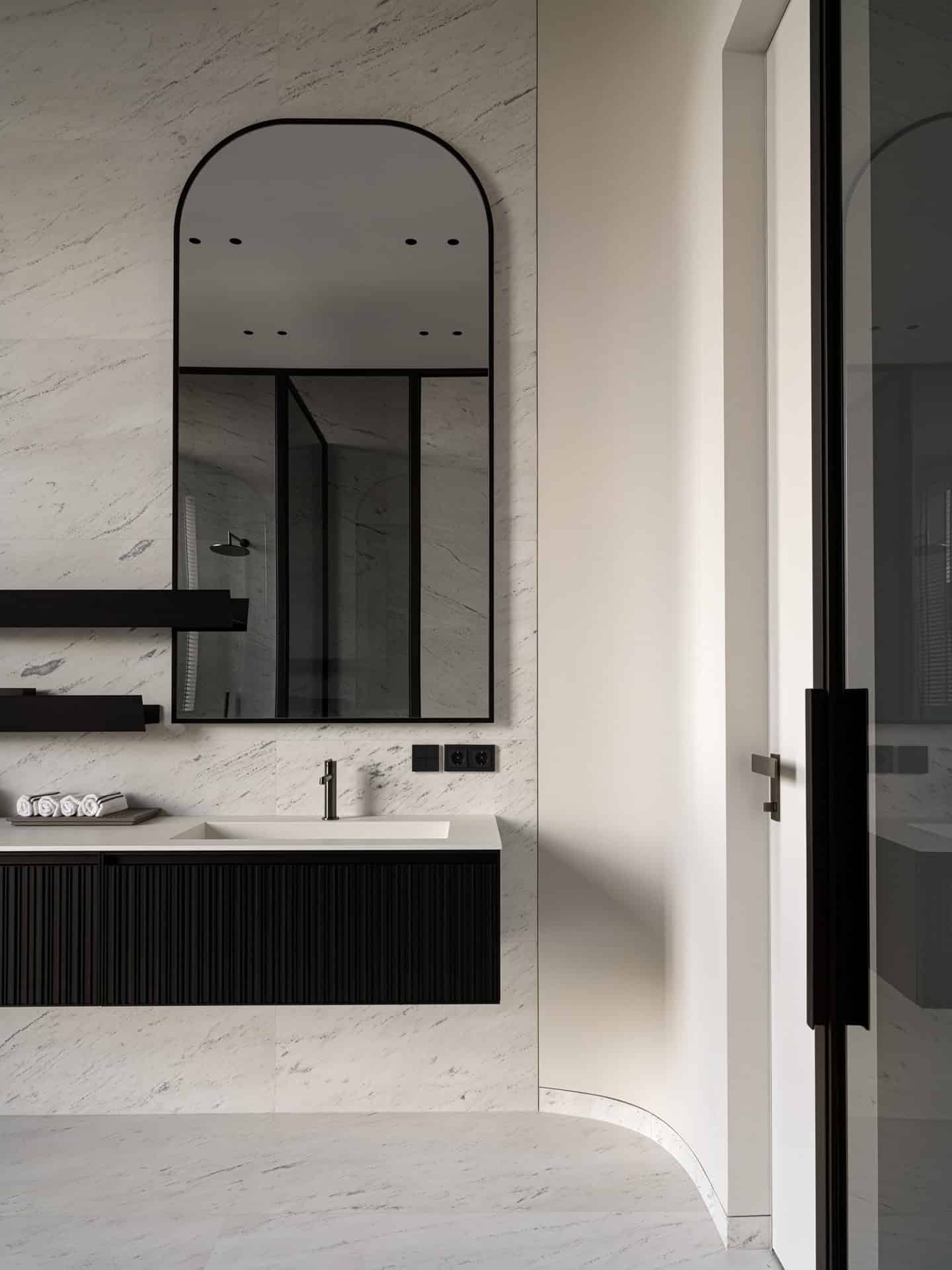 Arched Mirror Floating Bathroom Vanity Bathroom with arched mirror and floating vanity set against marble walls.