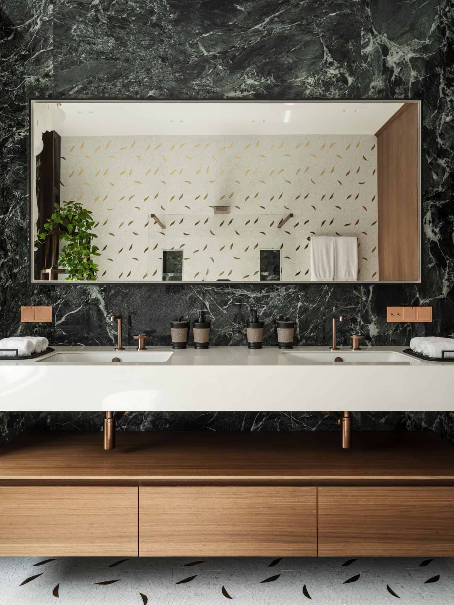 Bathroom Vanity with Dark Marble and Copper Fixtures Modern bathroom vanity with dark marble wall and copper hardware.
