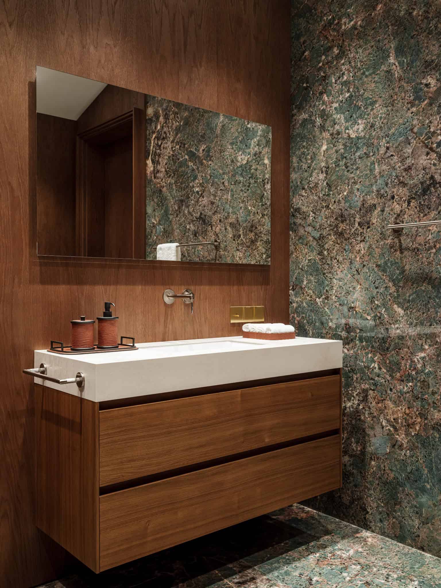 Bathroom Vanity with Walnut Paneling Modern floating vanity with warm walnut paneling and rectangular mirror.