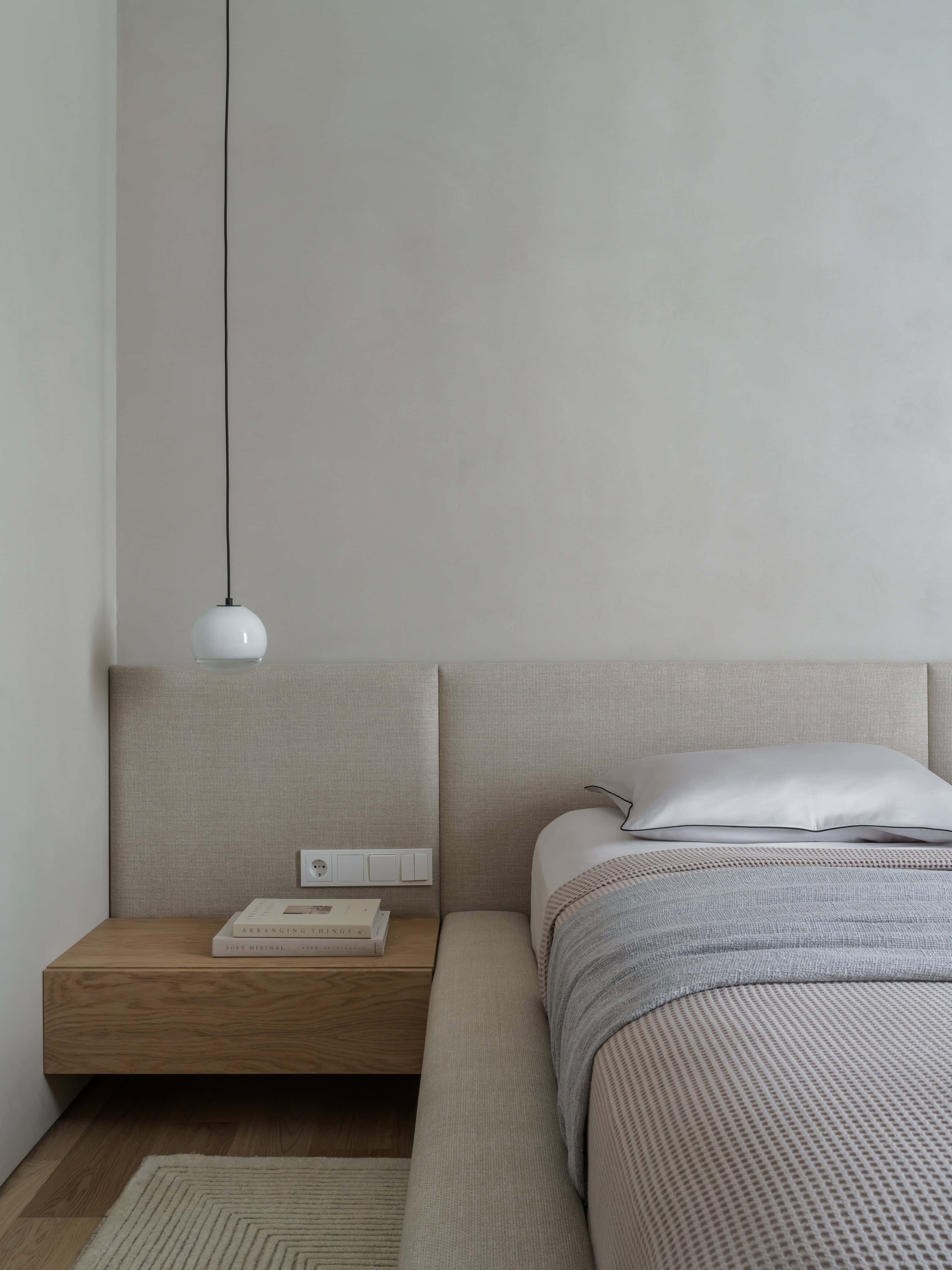 Bedside Table with Pendant Light Contemporary pendant light hanging over a wooden bedside table with modern books.