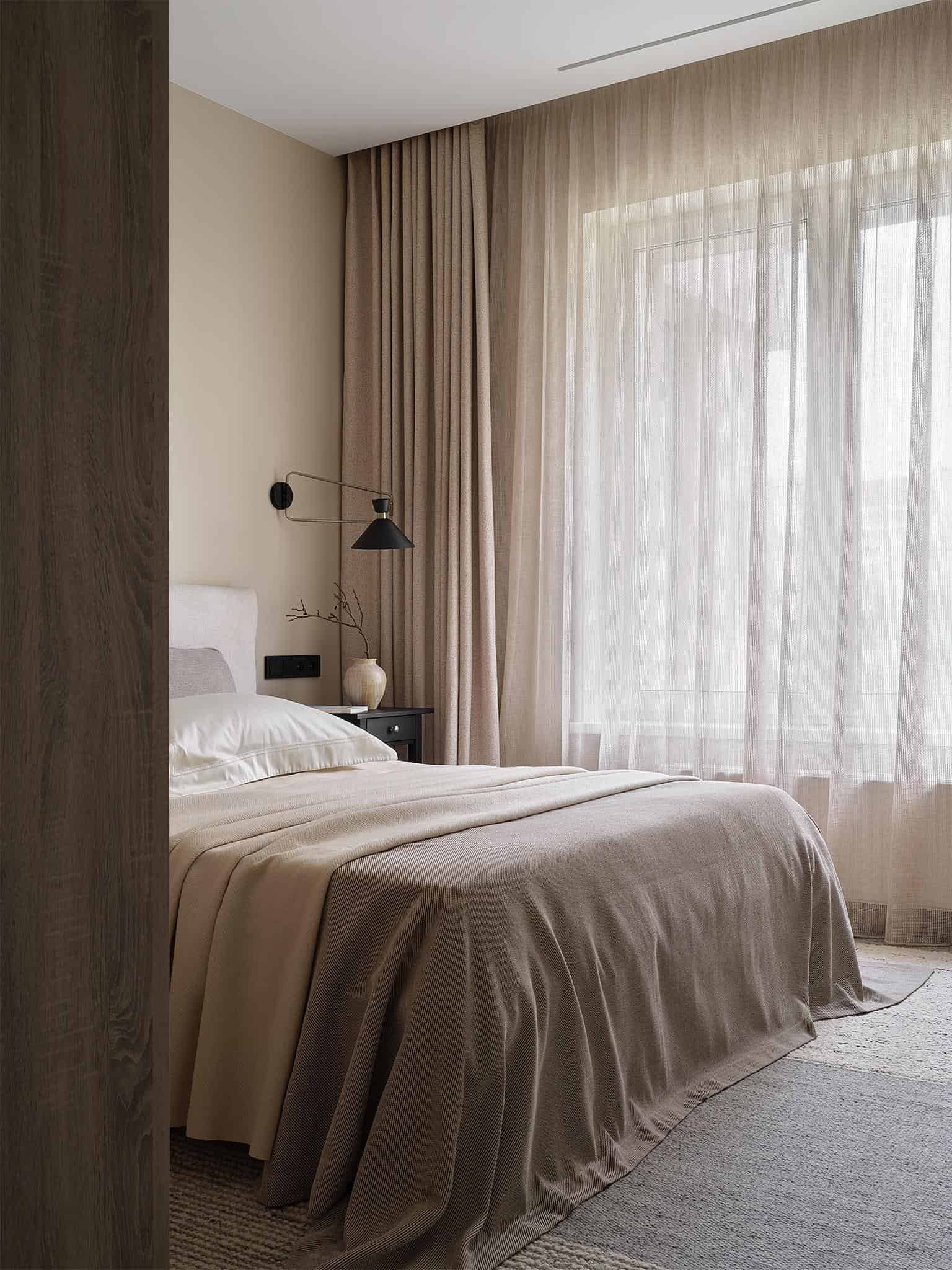 Beige Bedroom with Floor-to-Ceiling Sheer Curtains Beige bedroom featuring floor-to-ceiling sheer curtains and layered neutral bedding.