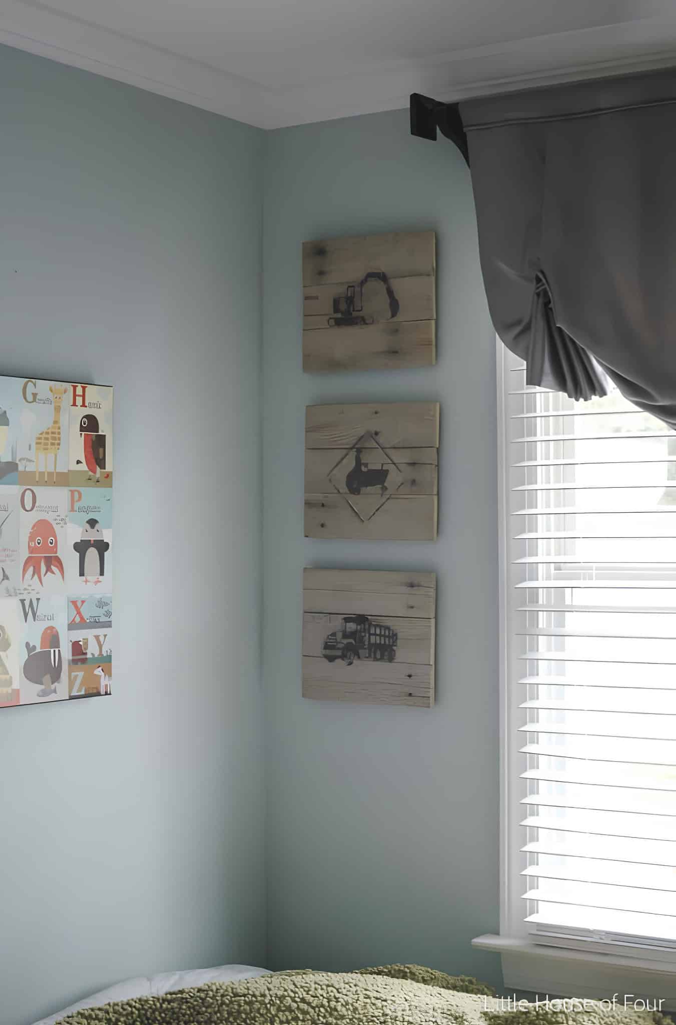 Set of three wood plaques featuring stenciled construction vehicles in a child's room corner.