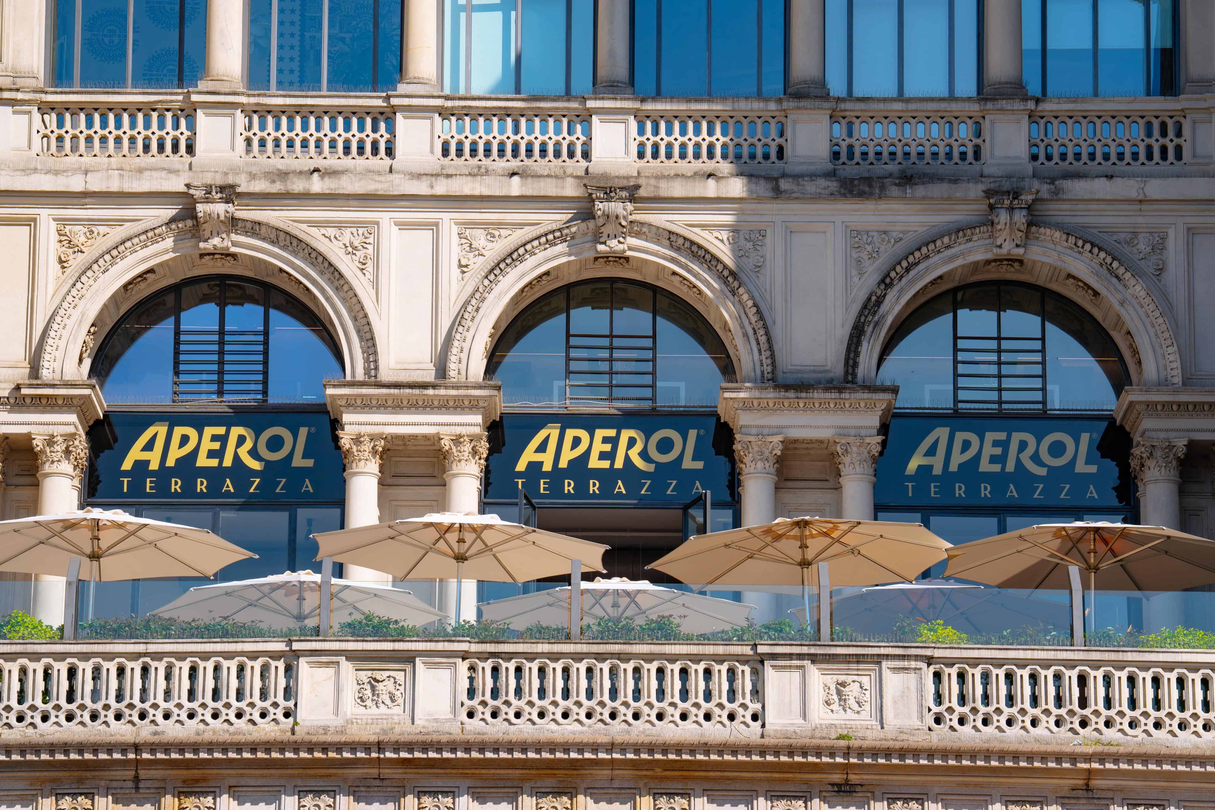 Close-Up Terrazza Aperol Arches Detail Close-up view of Terrazza Aperol's arched windows with branded signage and terrace umbrellas.