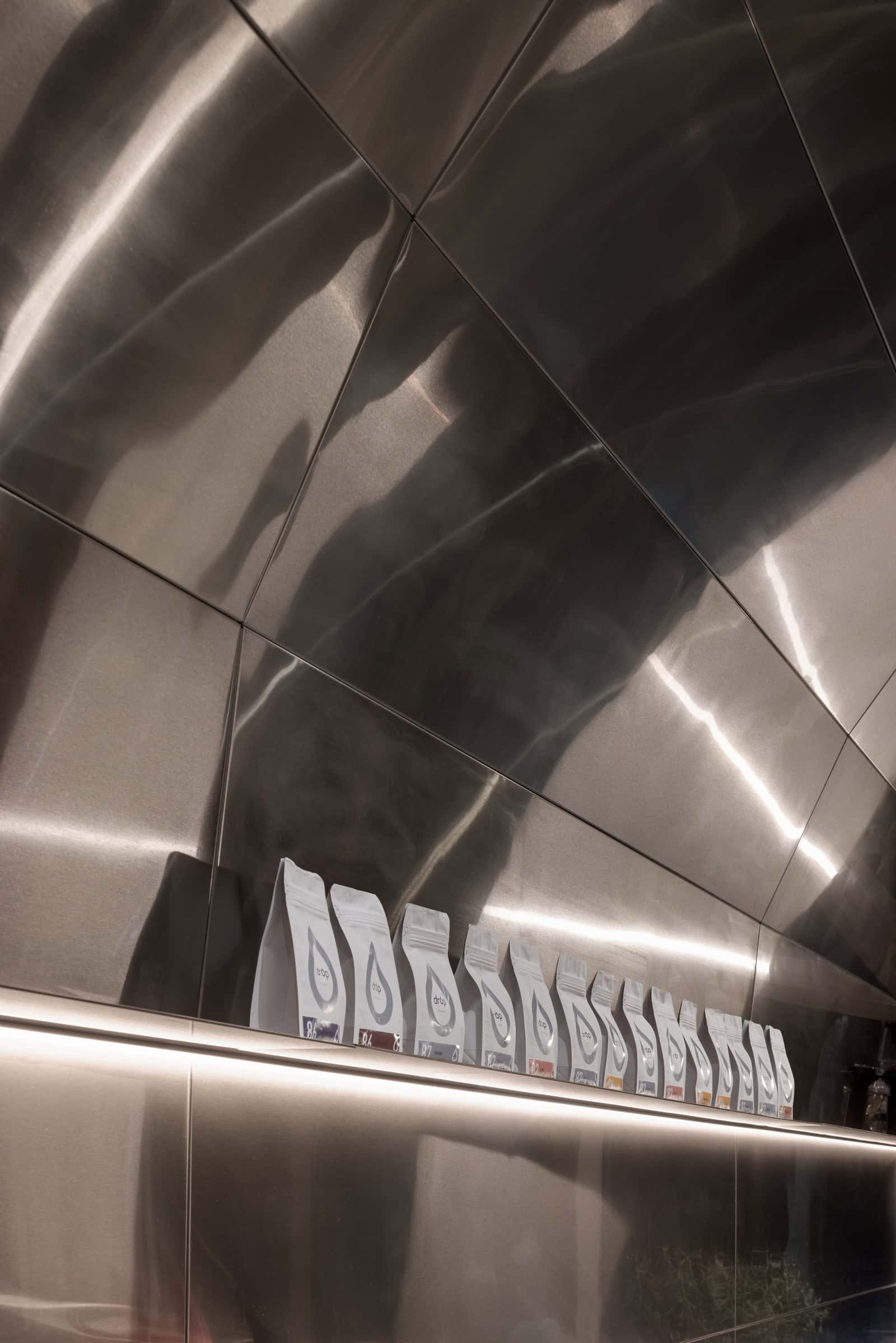 Coffee Shop Kovel Coffee Bean Shelf Coffee bean bags displayed on steel shelf with ambient lighting