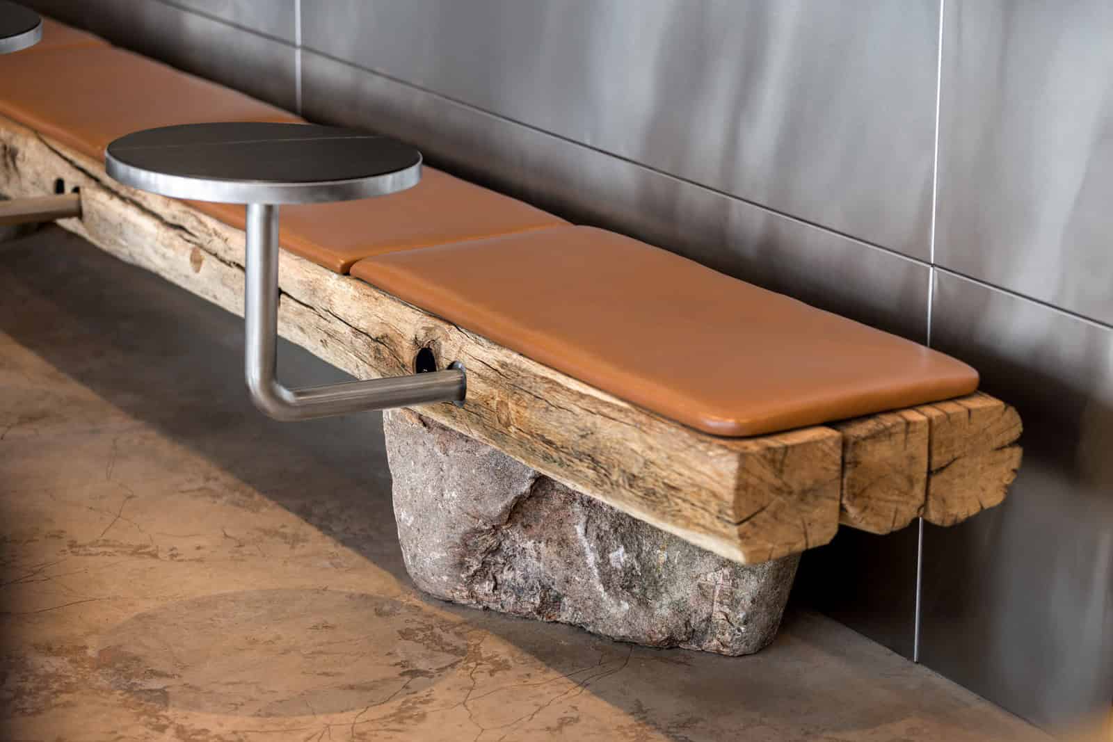 Coffee Shop Kovel Leather Wooden Bench Closeup Close-up of bench with leather seat, natural wood, and stone support in a modern cafe