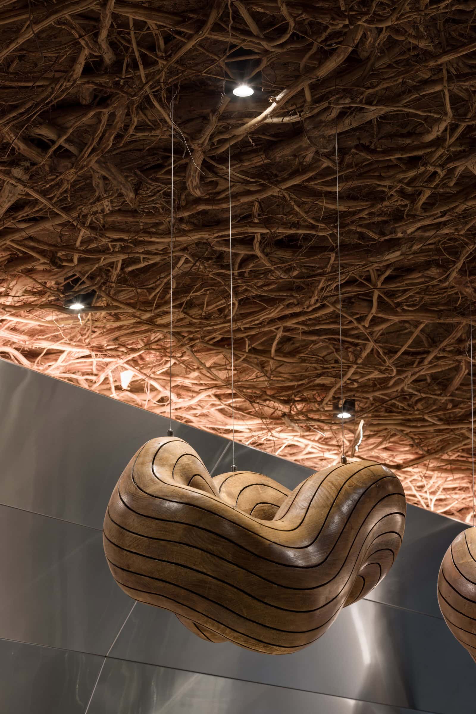 Coffee Shop Kovel Organic Light Fixture Closeup Close-up of sculptural wooden pendant light against natural twig ceiling