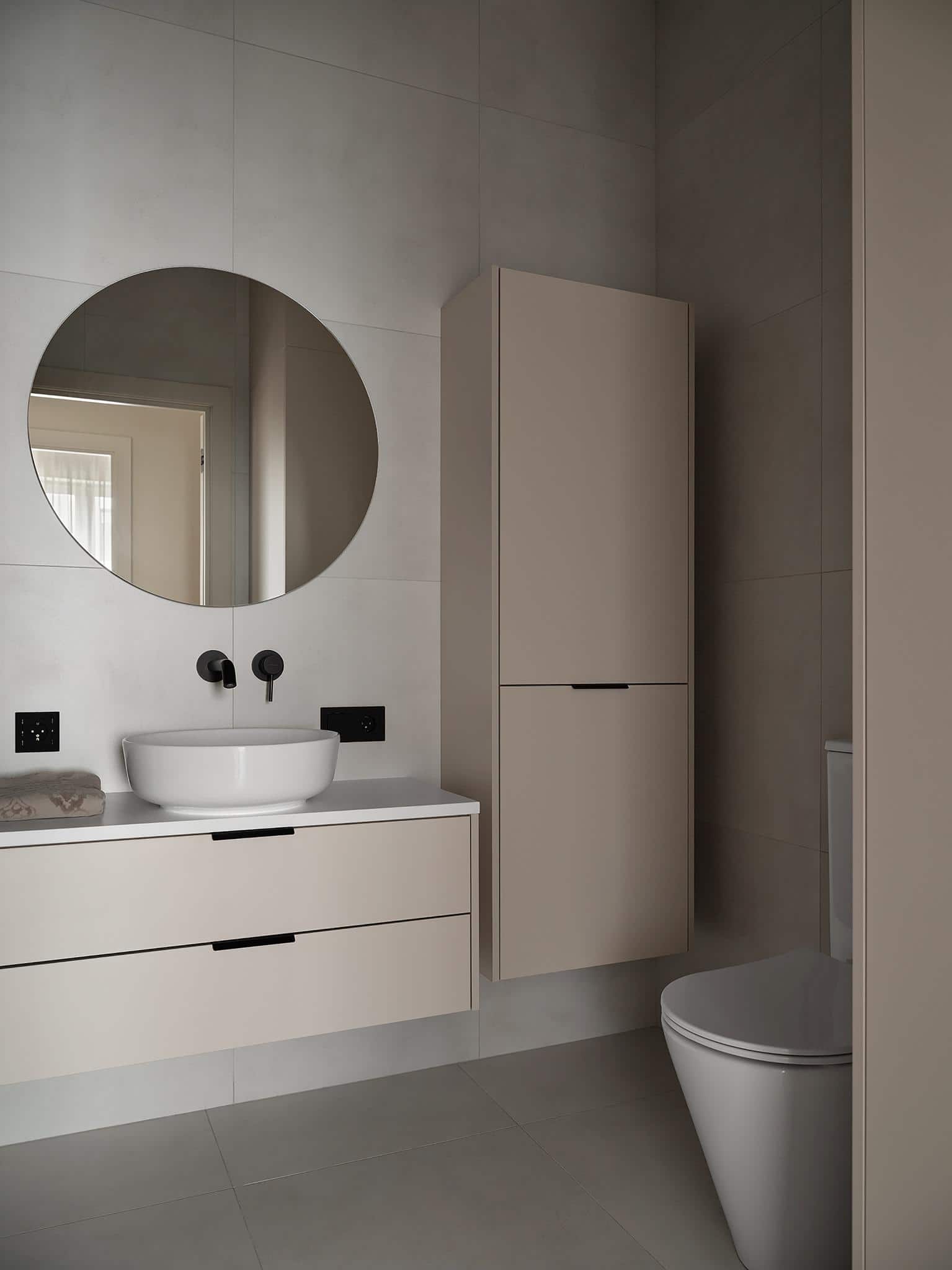 Contemporary Bathroom with Wall-Mounted Cabinet Contemporary bathroom with floating vanity, round mirror, and vertical wall cabinet.