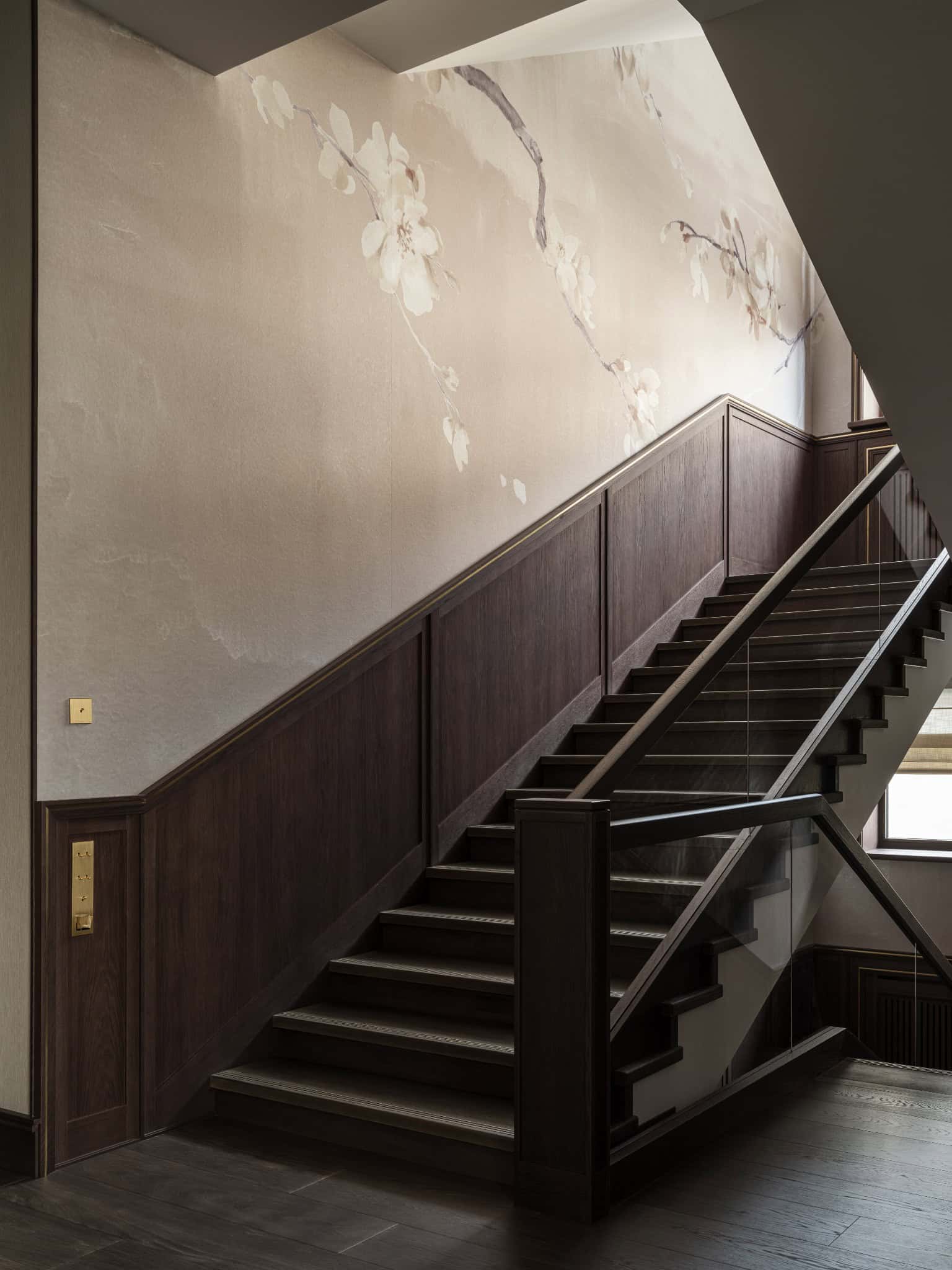 Dark Staircase with Illuminated Wall Art Wood-paneled staircase with soft lighting and textured floral mural.