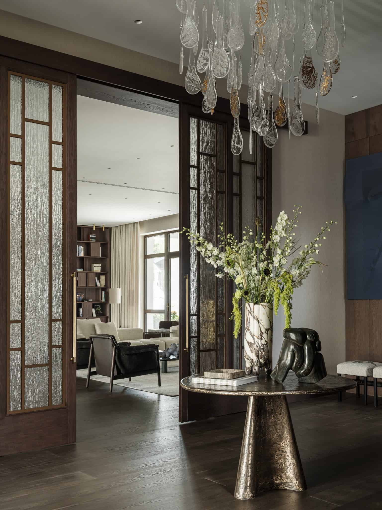 Detailed Shot of Foyer Floral Arrangement Close-up of marble vase with white and green floral arrangement on bronze table.