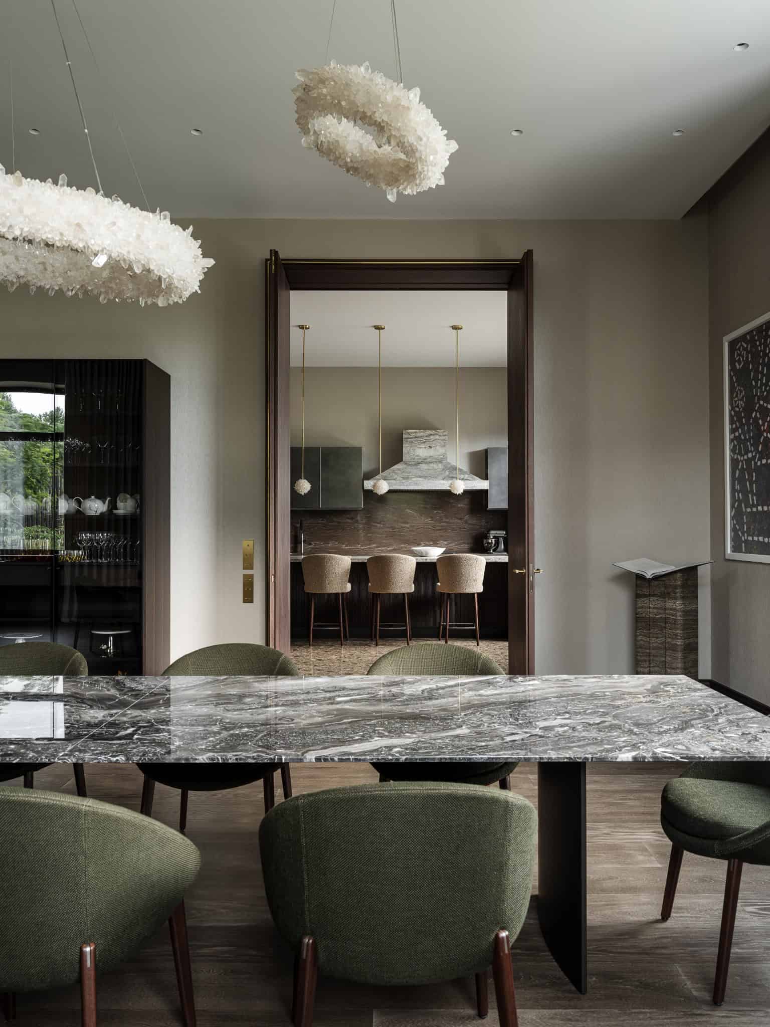 Dining Room View Into Luxury Kitchen Dining area with green chairs opening into modern kitchen space.
