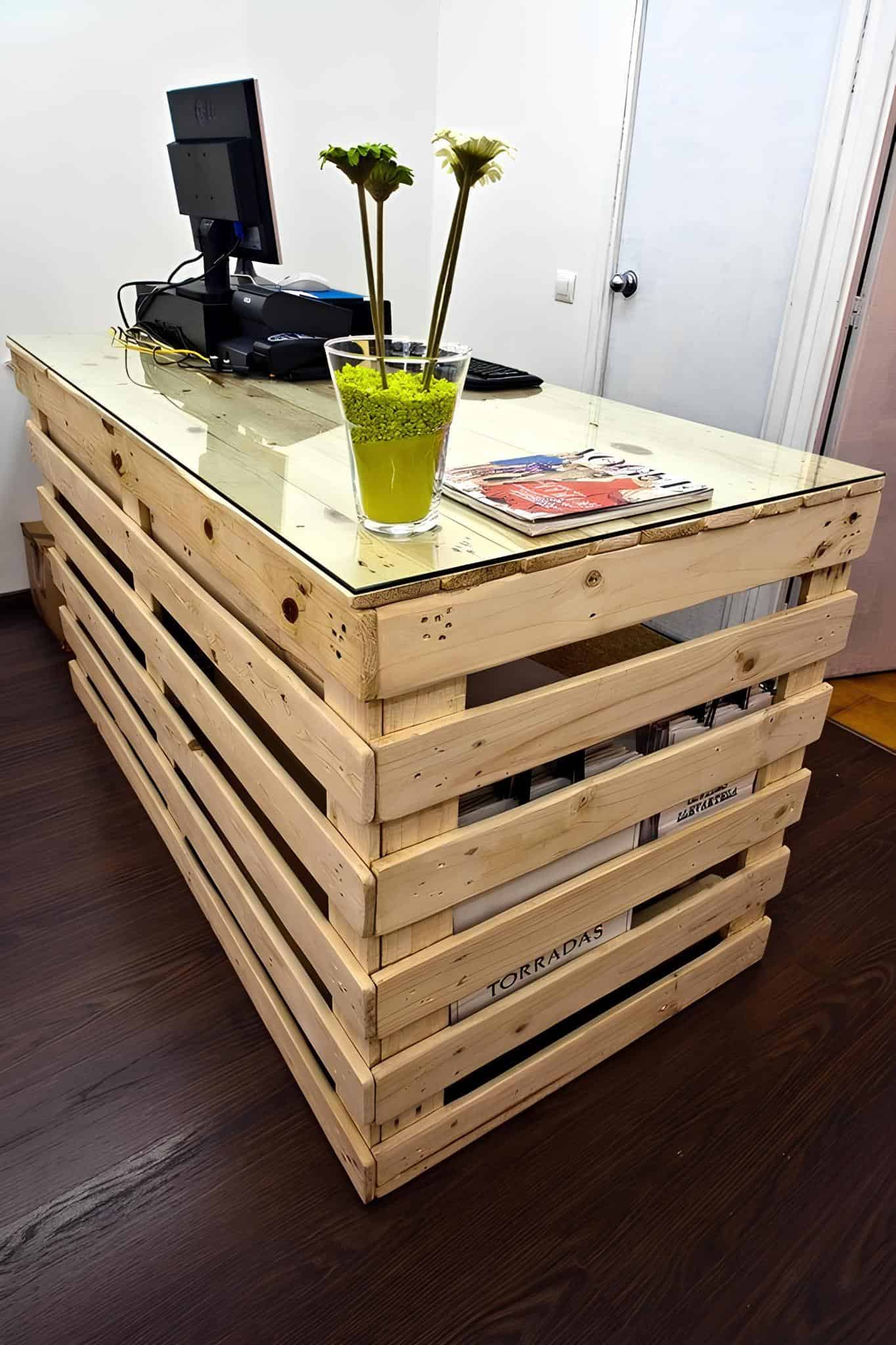 Reception desk made from light wood pallets with glass top and flowers