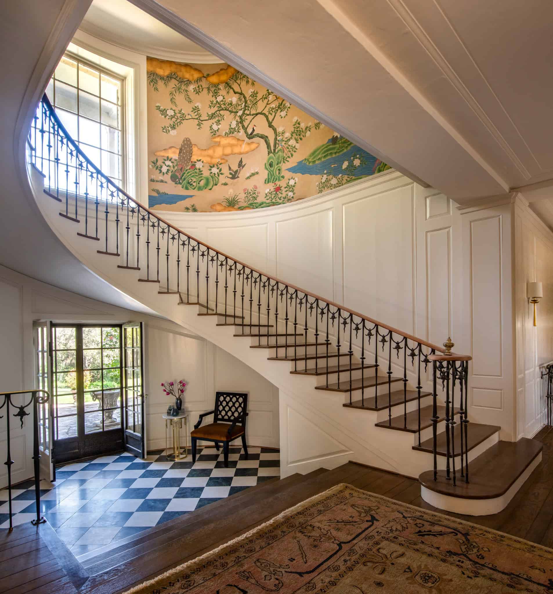 Entry Hallway Curved Staircase Halter Home Grand entry with a sweeping curved staircase and hand-painted wall mural.