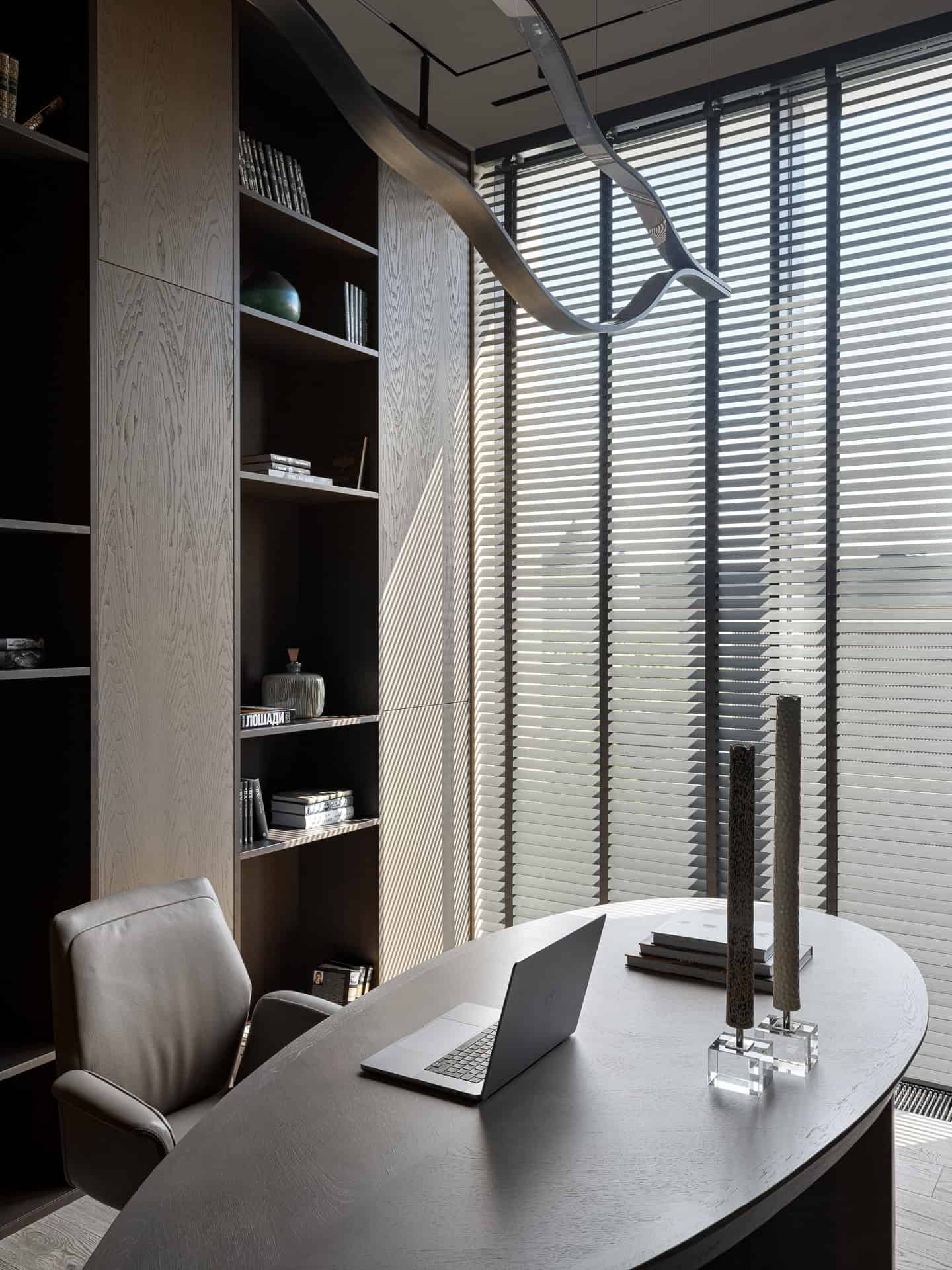 Executive Desk in Modern Library Curved executive desk in front of floor-to-ceiling bookshelves and large windows.