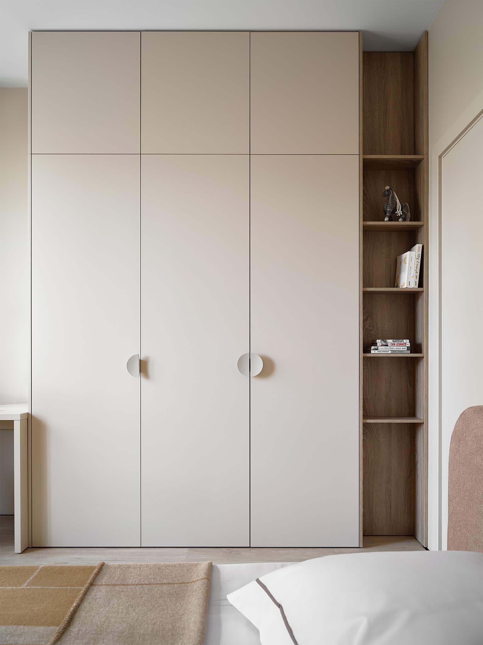 Floor-to-Ceiling Wardrobe with Open Shelving Tall wardrobe with beige cabinets and open wooden shelves next to a kids bed.
