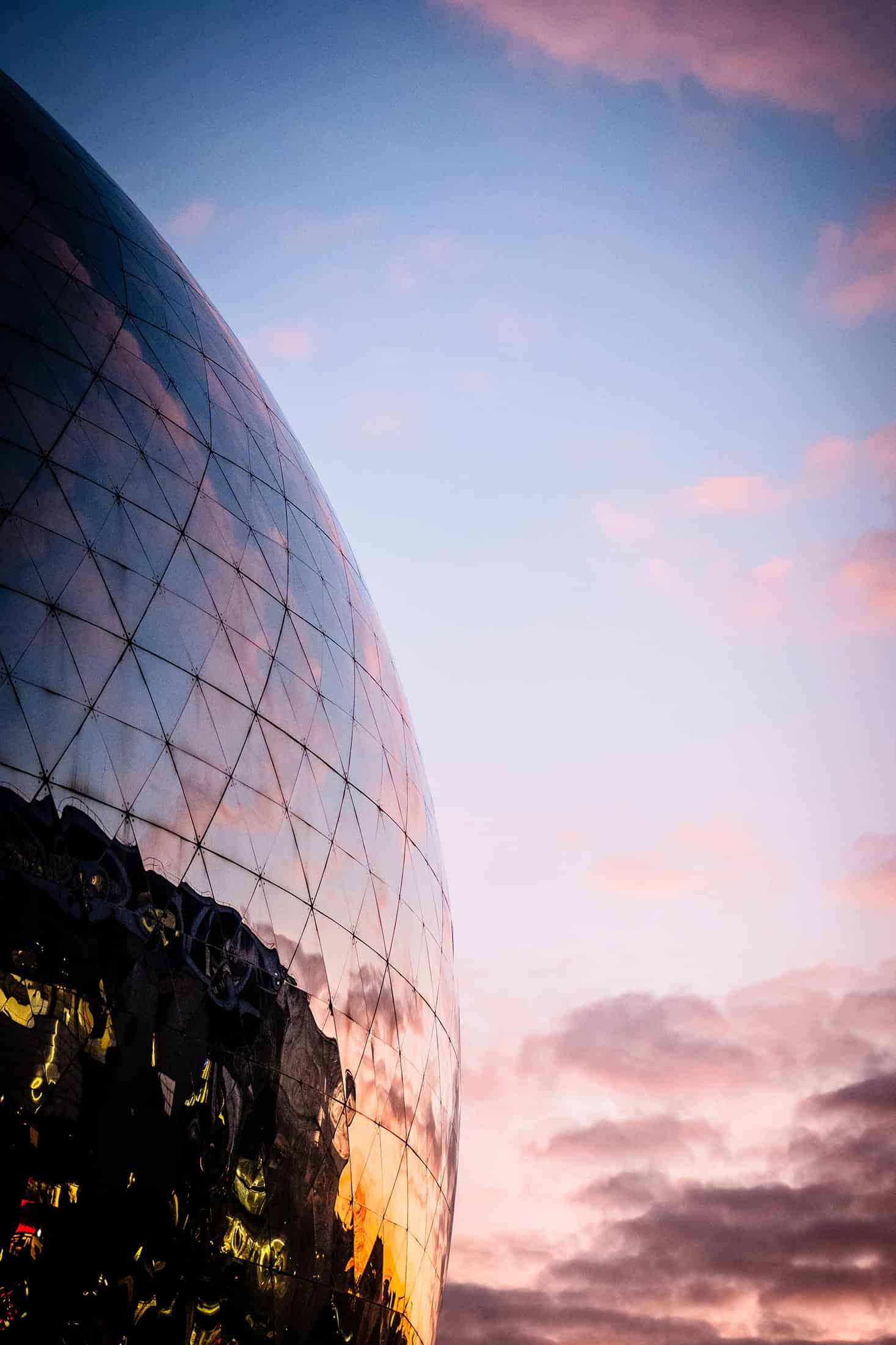 Geode Glass Sphere Sunset View Detail of La Géode's reflective dome at sunset with vibrant clouds.