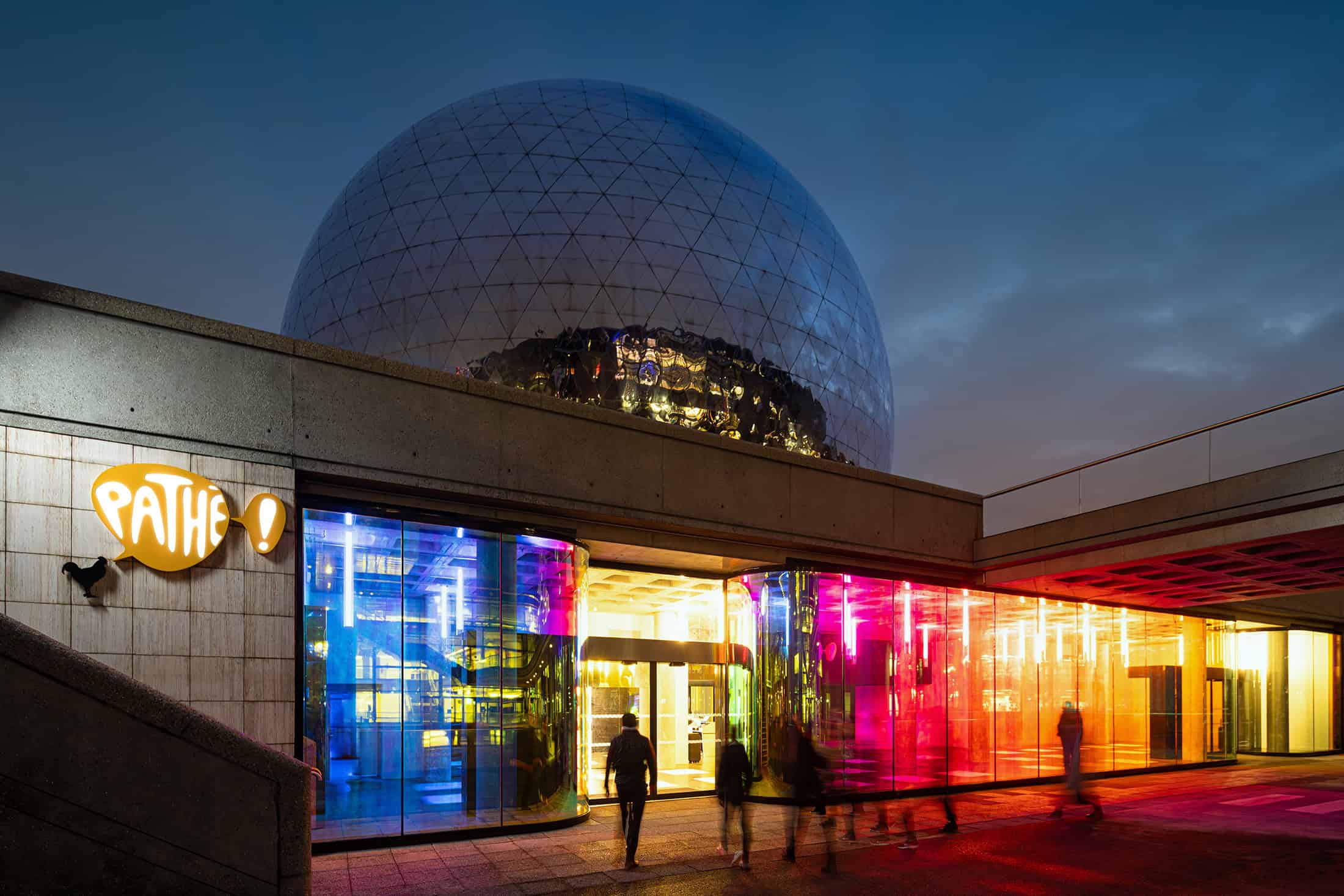Geode Night Exterior Colored Entry Exterior of La Géode with colorful glass facade illuminated at night.