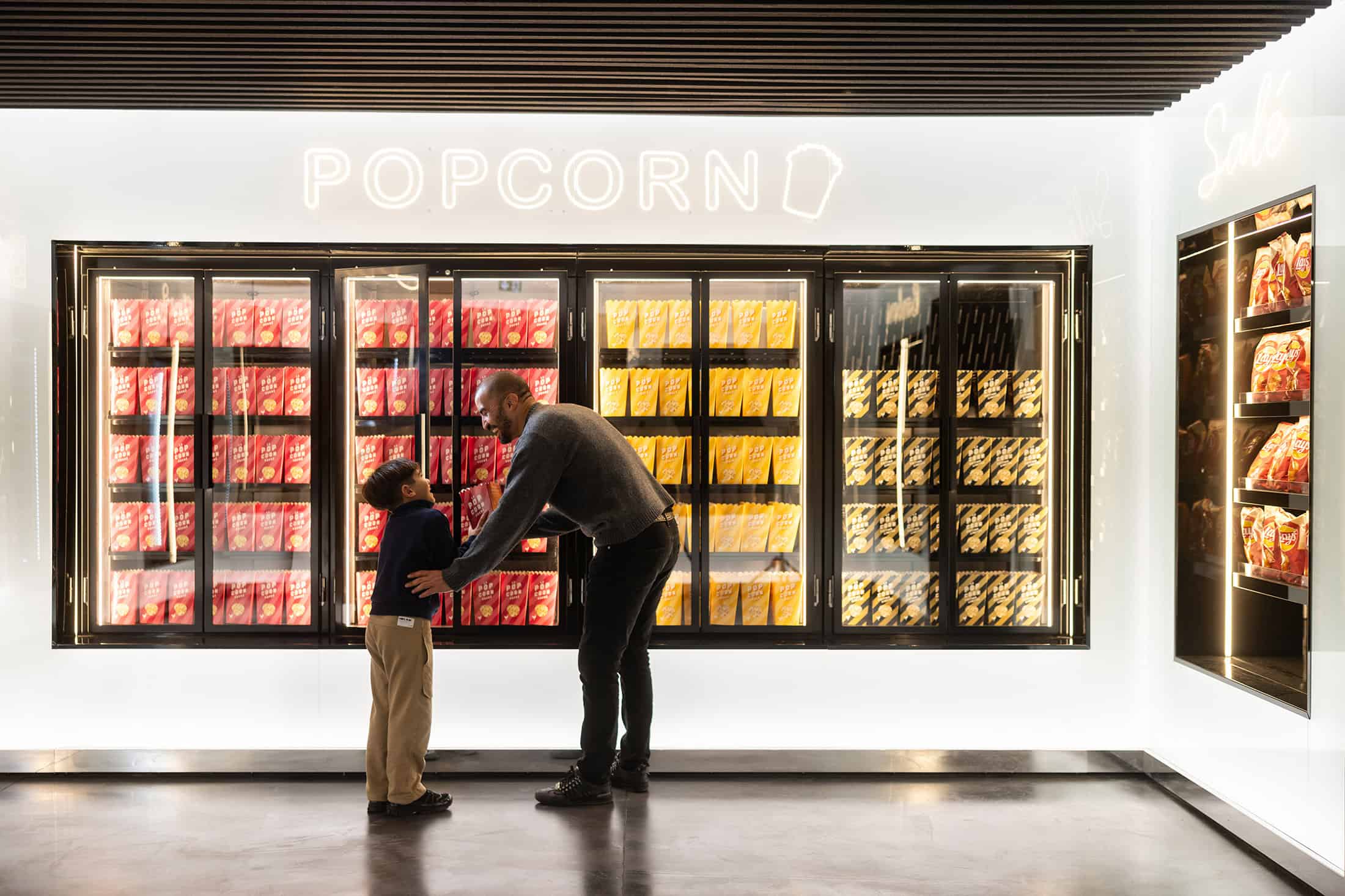 Geode Popcorn Wall Display Father and son at a vibrant popcorn display inside La Géode.