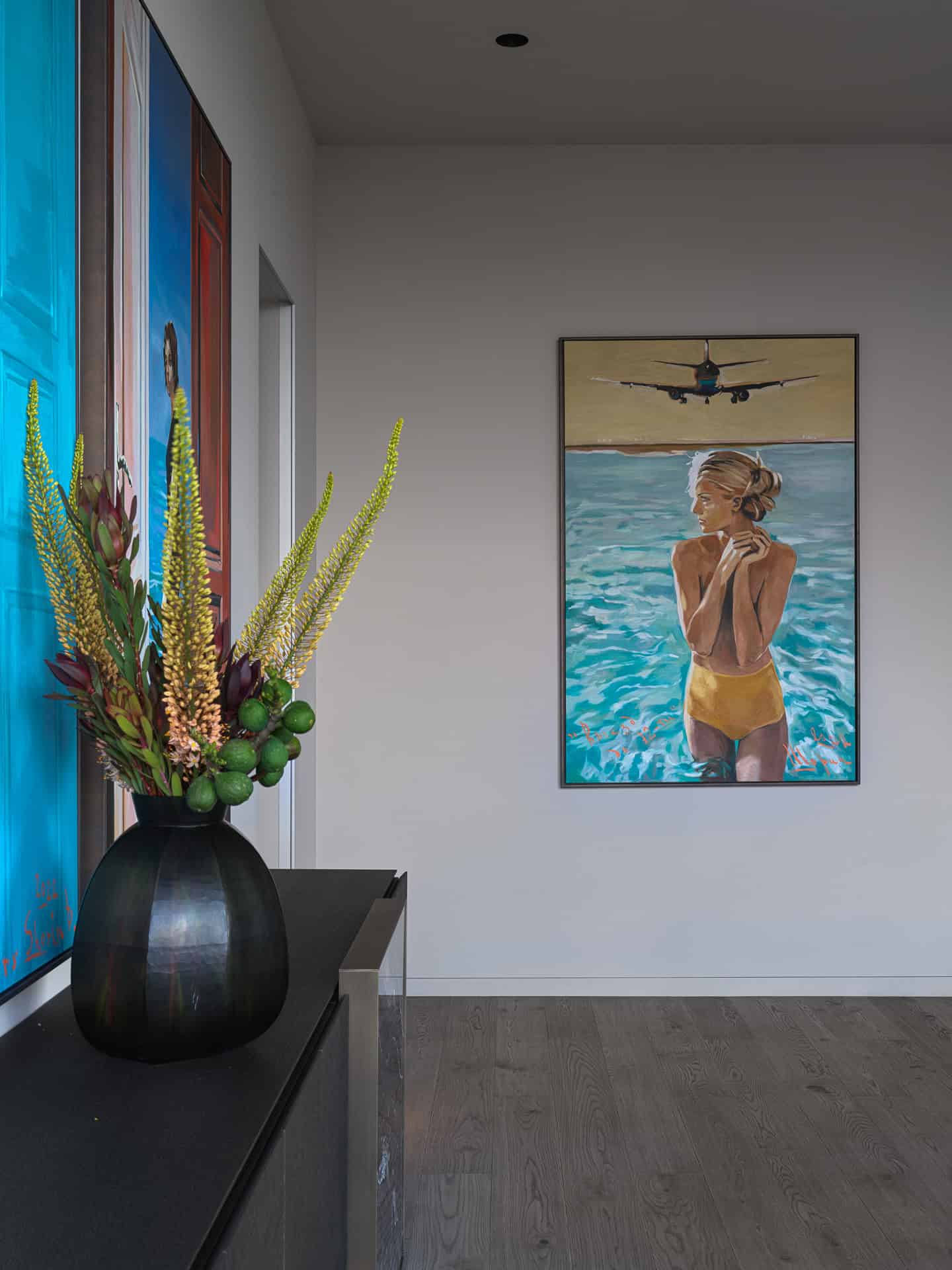 Hallway with Vibrant Portrait Paintings Bright hallway featuring colorful portrait paintings and floral arrangement.