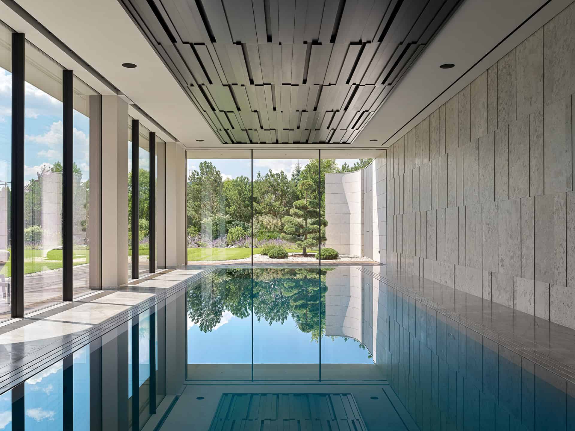Indoor Pool with Garden View Sleek indoor swimming pool with floor-to-ceiling glass offering a lush garden view.