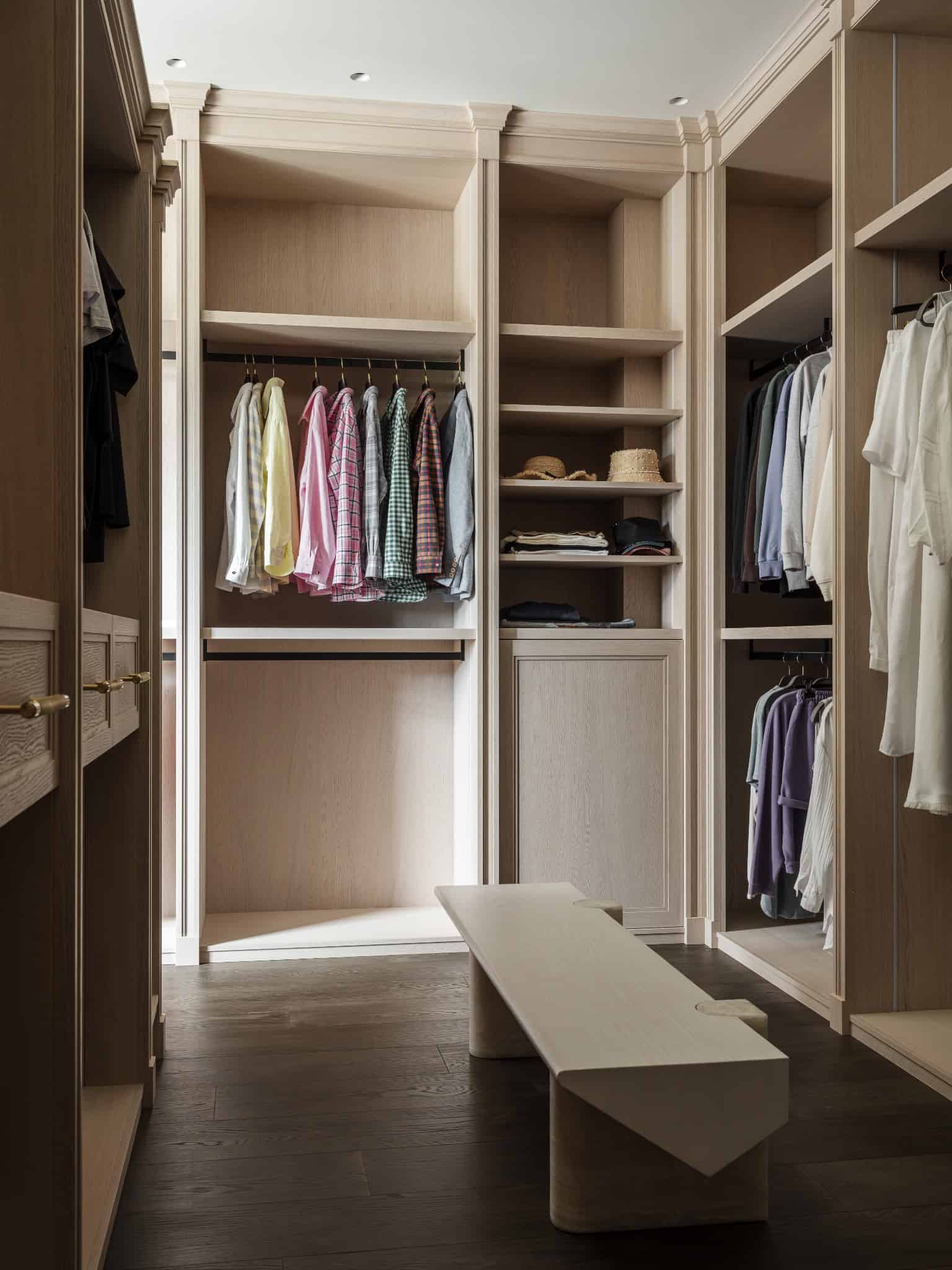 Light Wood Dressing Room with Bench Spacious walk-in closet with light wood cabinetry and a central bench.