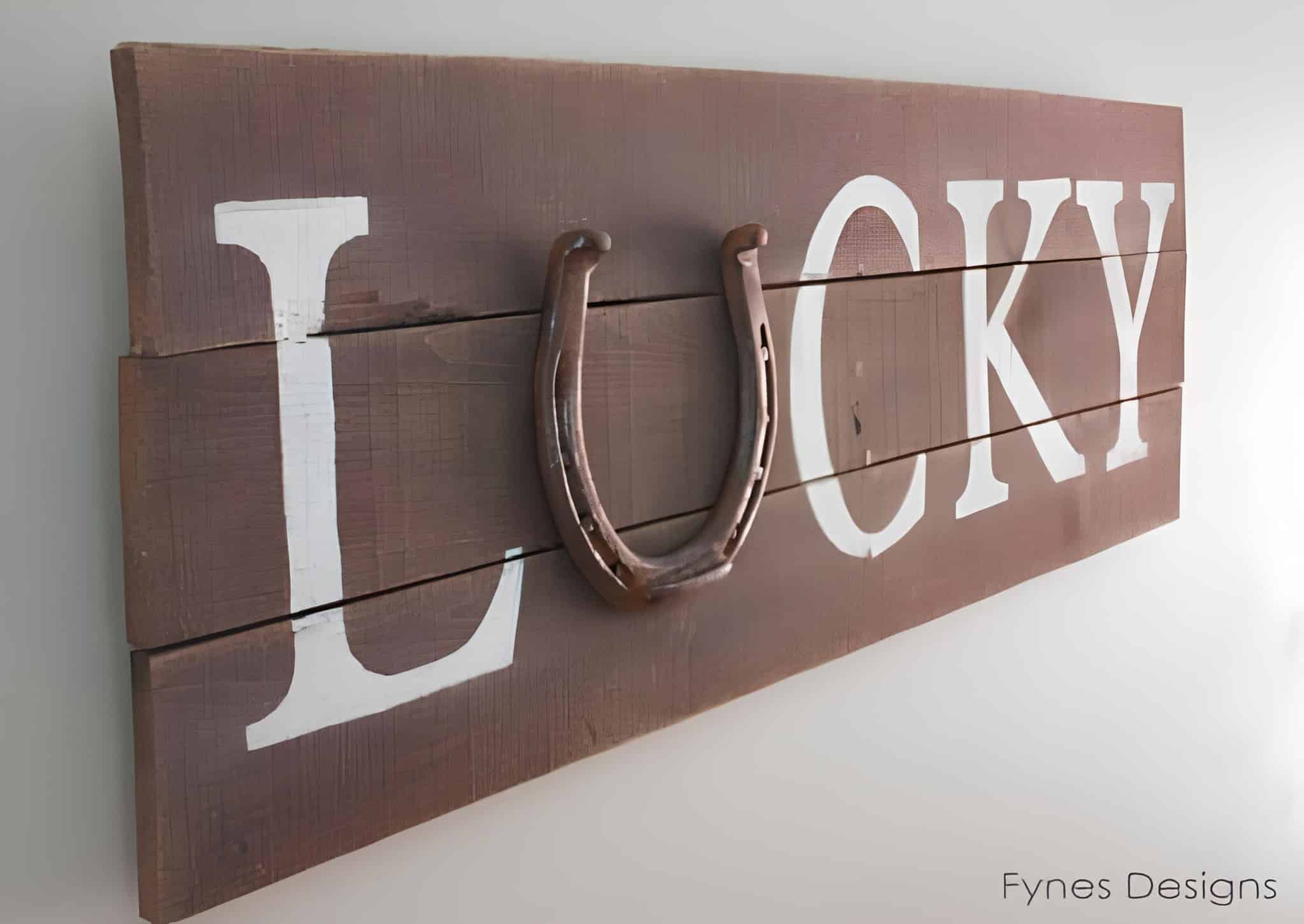 Rustic wooden sign spelling 'LUCKY' with a metal horseshoe replacing the U.