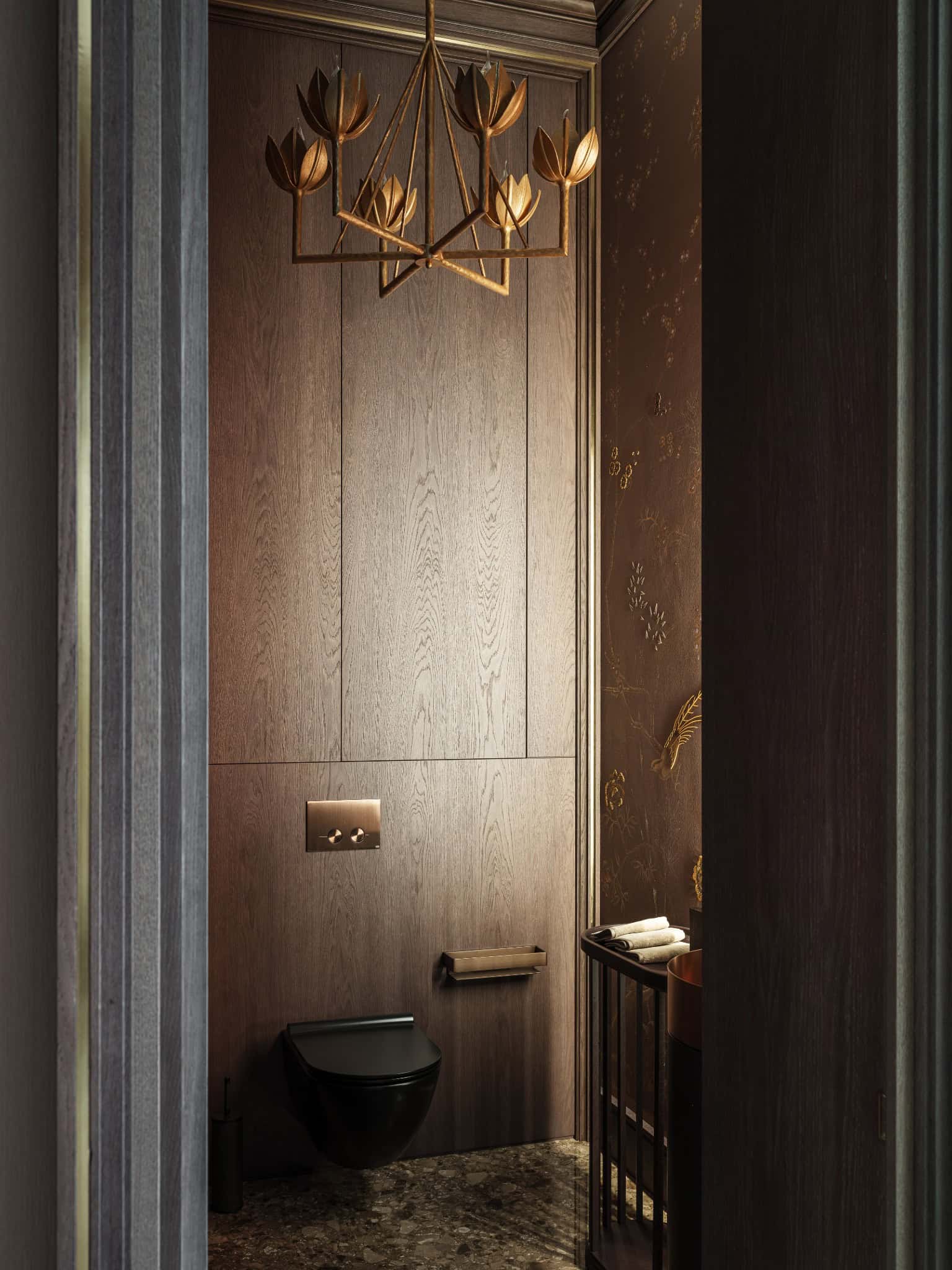 Luxury Powder Room with Gold Lighting Elegant powder room with dark wood walls and sculptural gold chandelier.