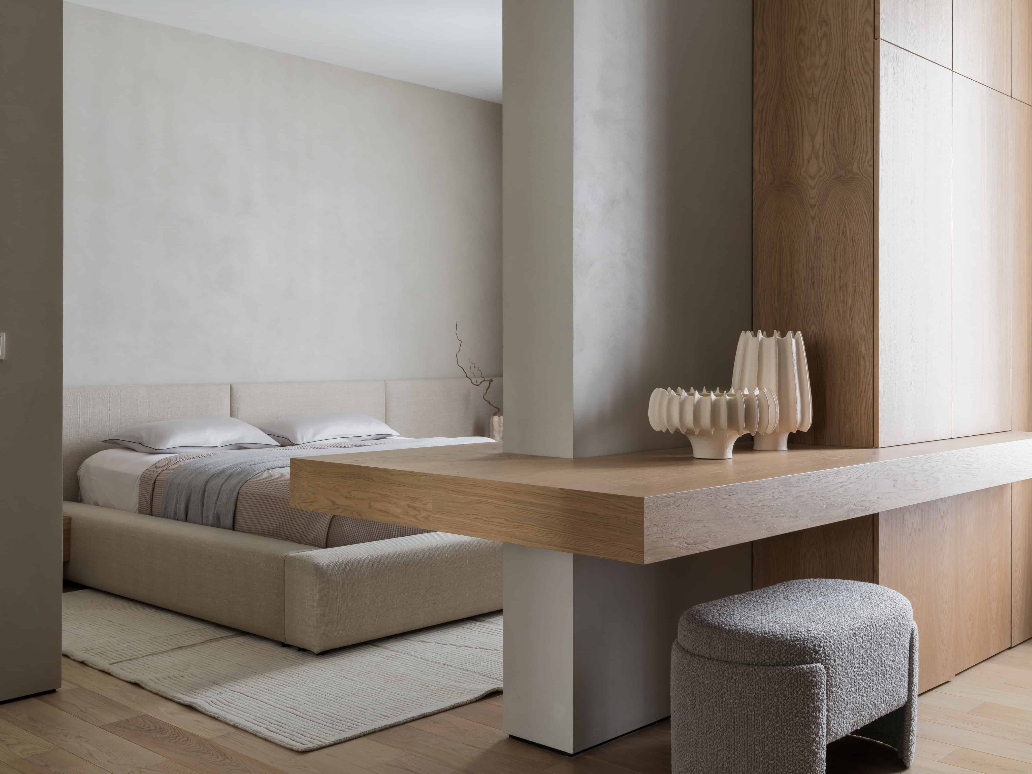 Minimalist Bedroom Desk With Decor Floating wooden vanity in bedroom with sculptural vases and built-in storage wall.