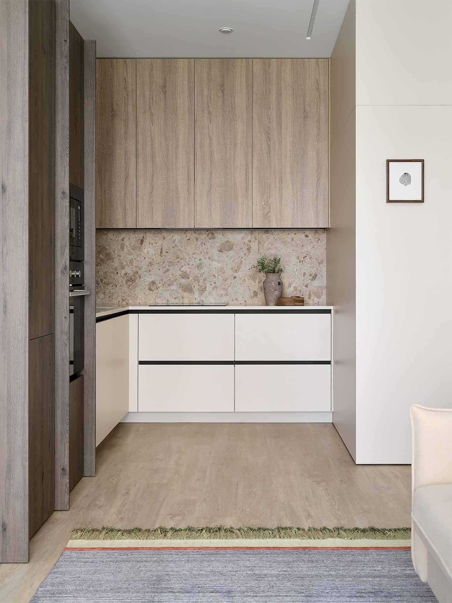 Minimalist Beige Kitchen with Stone Backsplash Minimalist beige kitchen with clean cabinetry and natural stone backsplash.