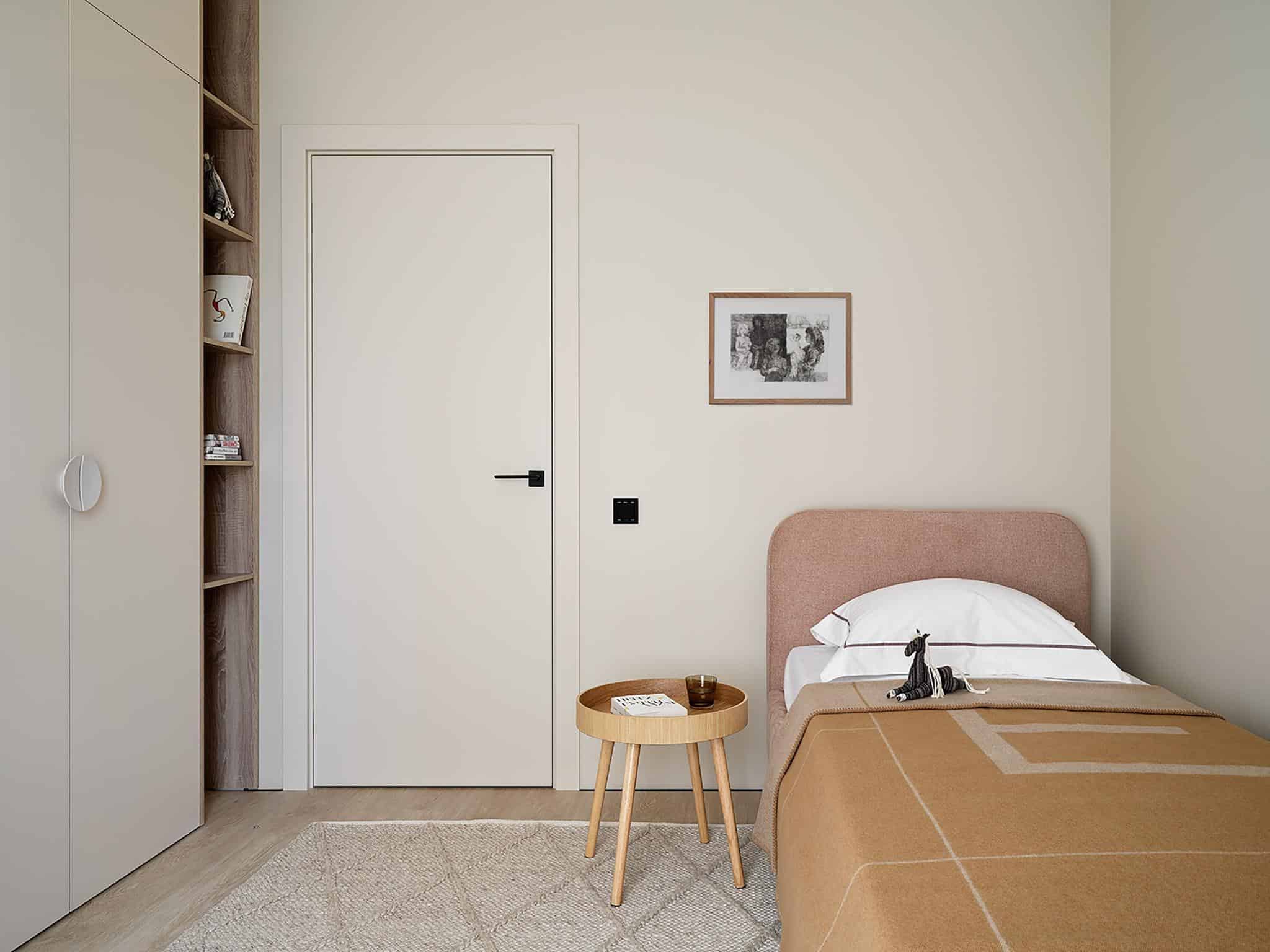Minimalist Kids Bedroom in Beige Apartment Minimalist kids bedroom with a beige color palette, soft headboard, and built-in storage shelves.