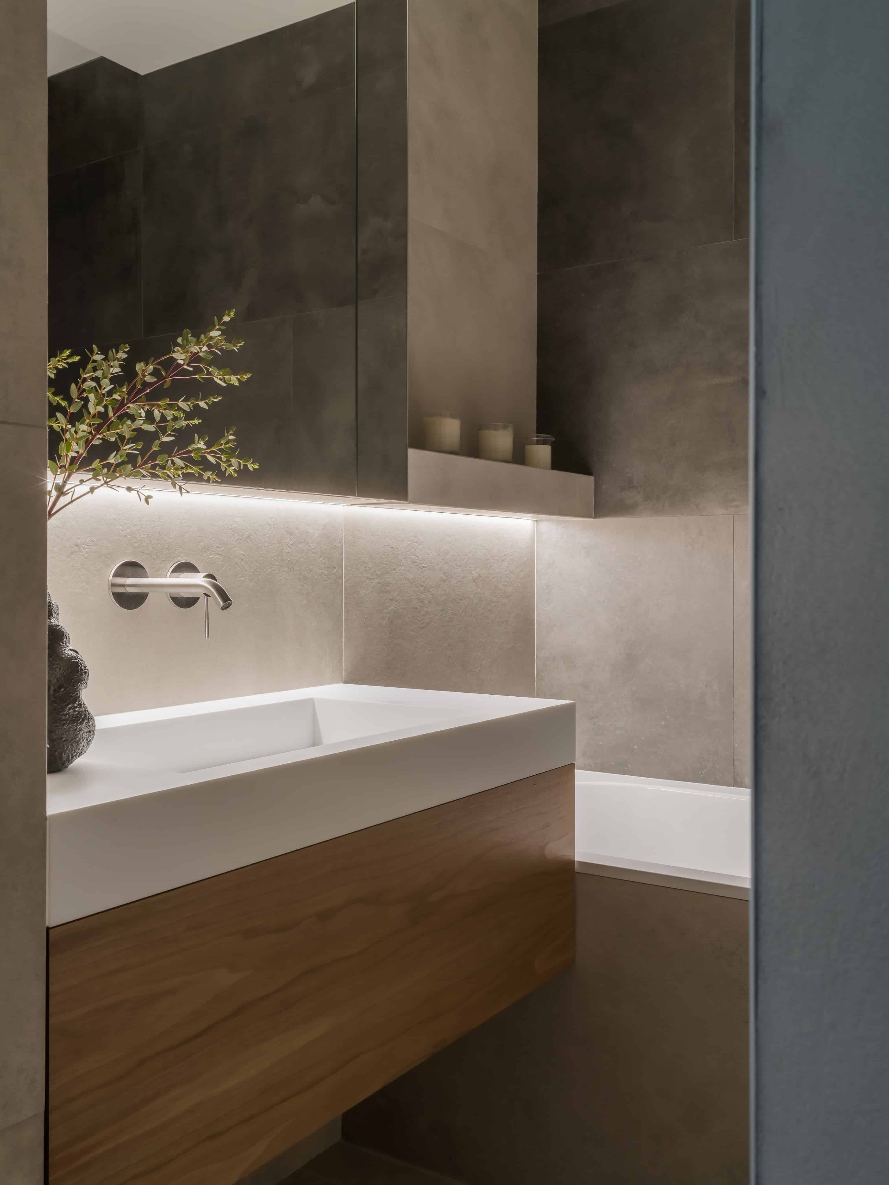 Minimalist Modern Bathroom Vanity Lighting Floating bathroom vanity with under-lighting and dark tile backdrop for a sleek, minimalist effect.