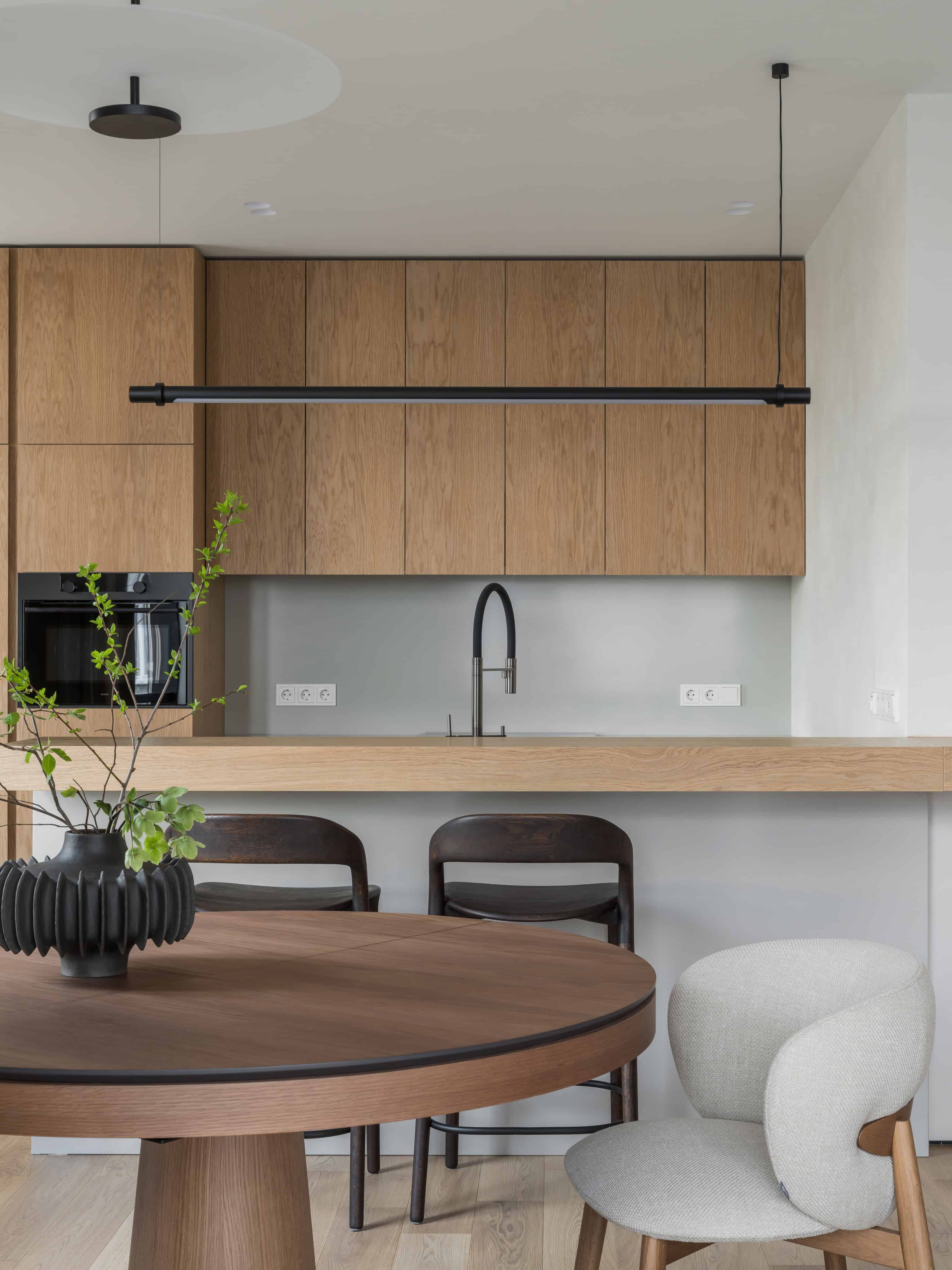 Minimalist Modern Dining Kitchen Design 4 Kitchen island with black fixtures and wooden bar stools in a soft minimalist setting.