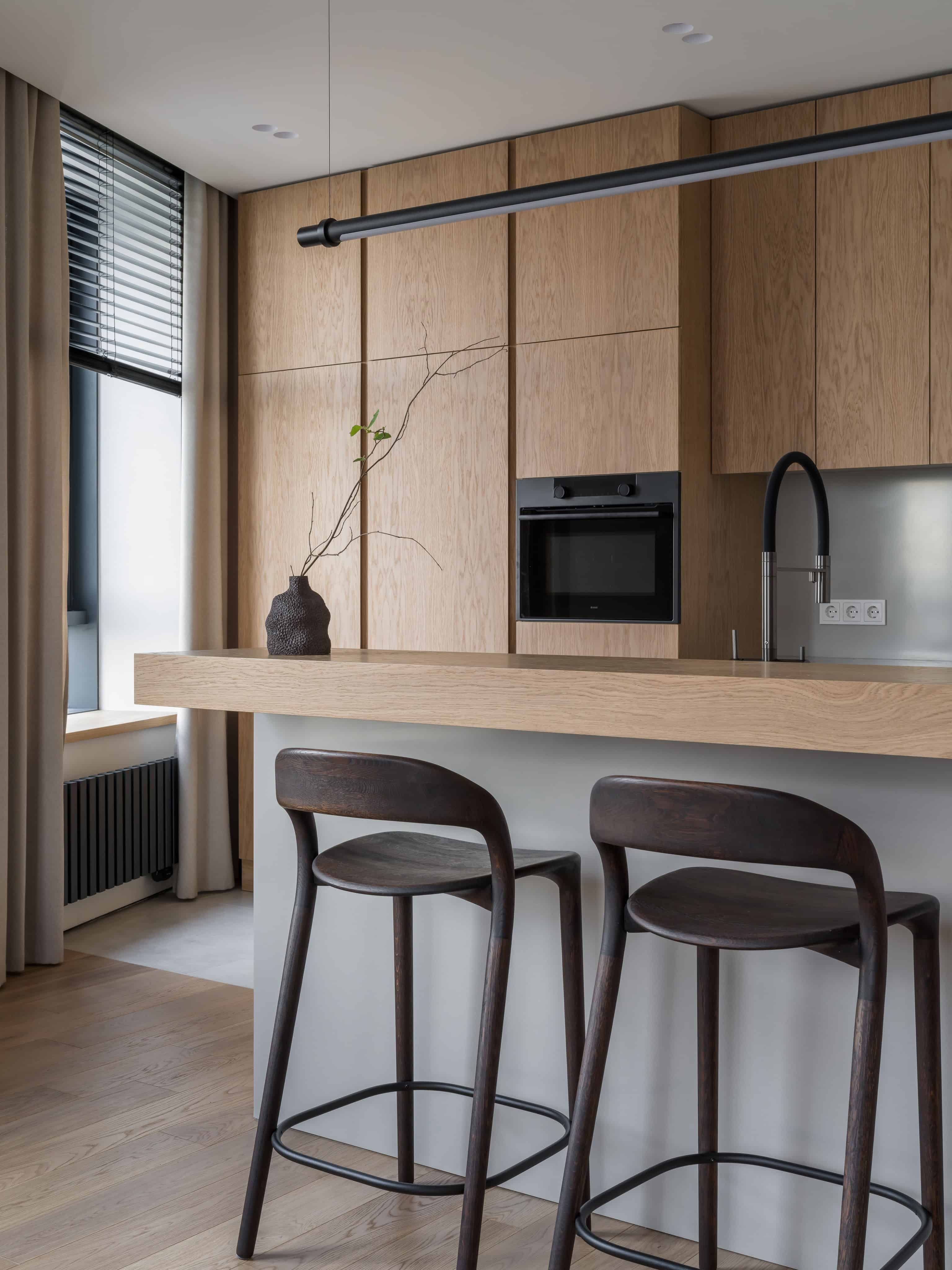 Minimalist Modern Dining Kitchen Design 6 View of bar seating and neutral-toned cabinetry with vertical grain wood panels.