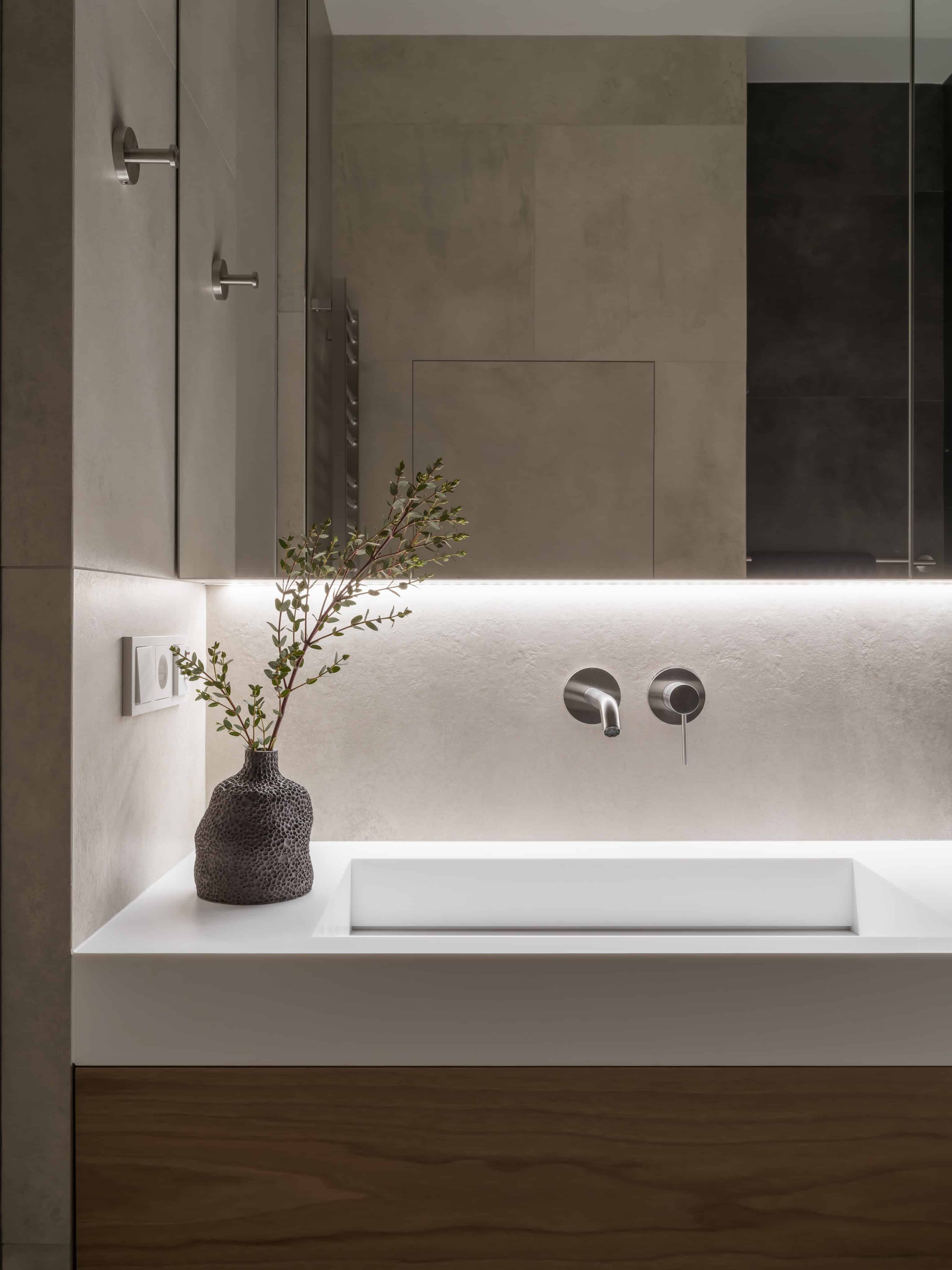 Modern Bathroom Sink Detail With Light Minimalist bathroom sink with LED backlight and built-in storage in neutral-toned walls.