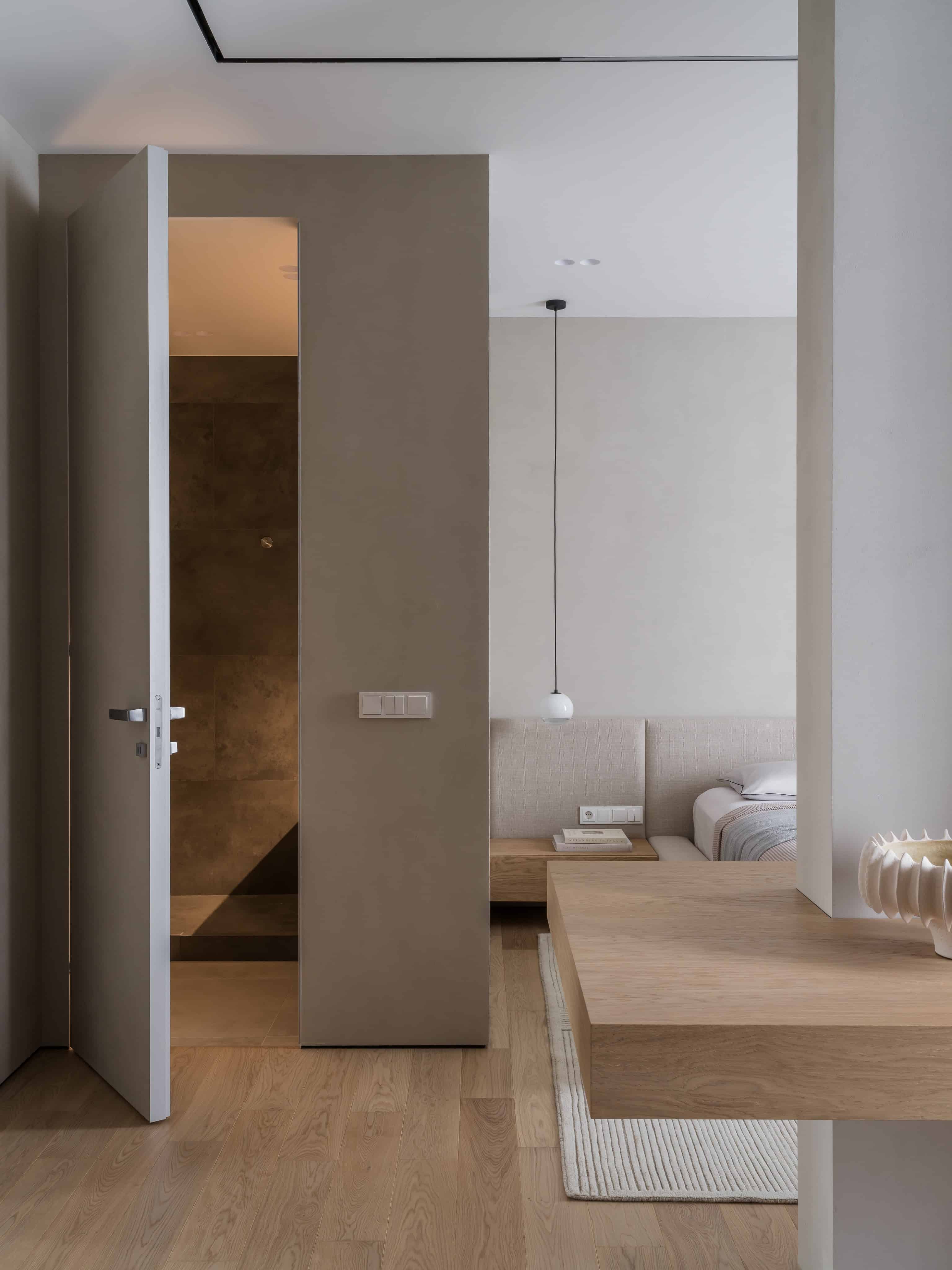 Modern Bedroom Suite View With Bathroom Cozy modern suite with view of bathroom entrance and wood floor continuity.