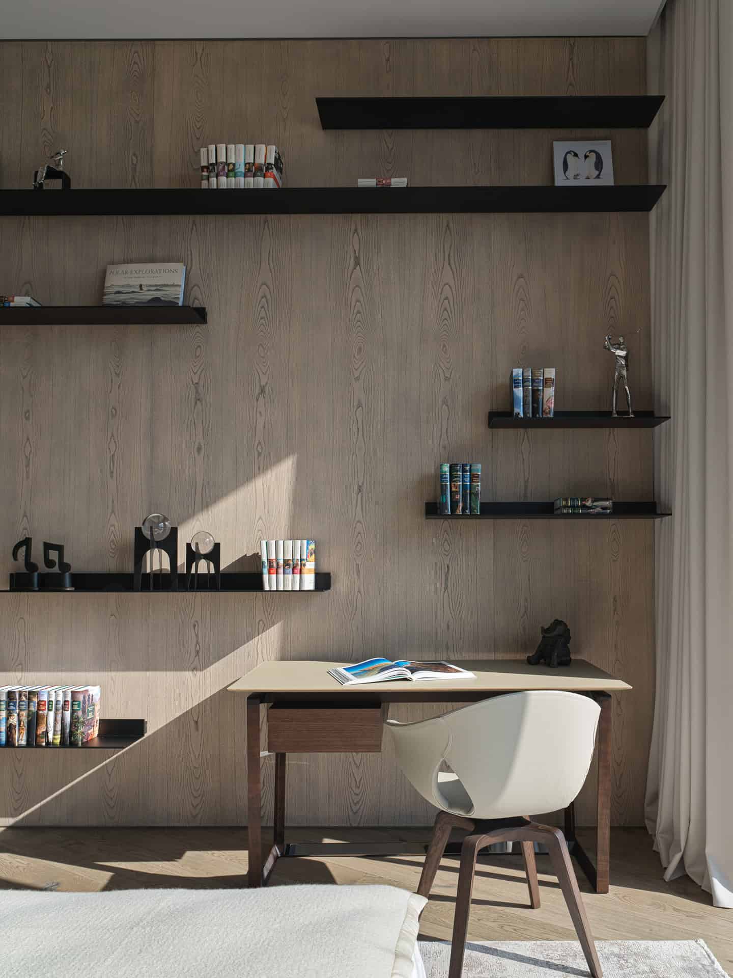 Modern Bookshelves Over Wood Wall Study area with floating bookshelves mounted over warm wood paneling.