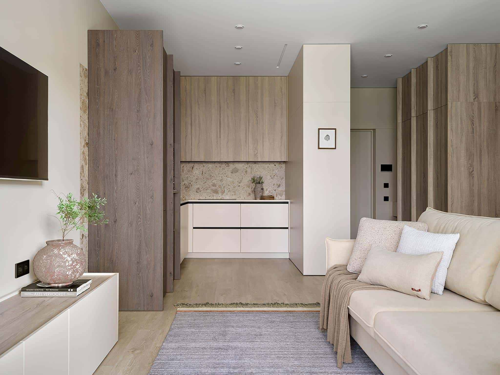 Open Plan Living Room and Kitchen Interior Open plan living space with beige sofa, built-in cabinetry, and neutral kitchen decor.