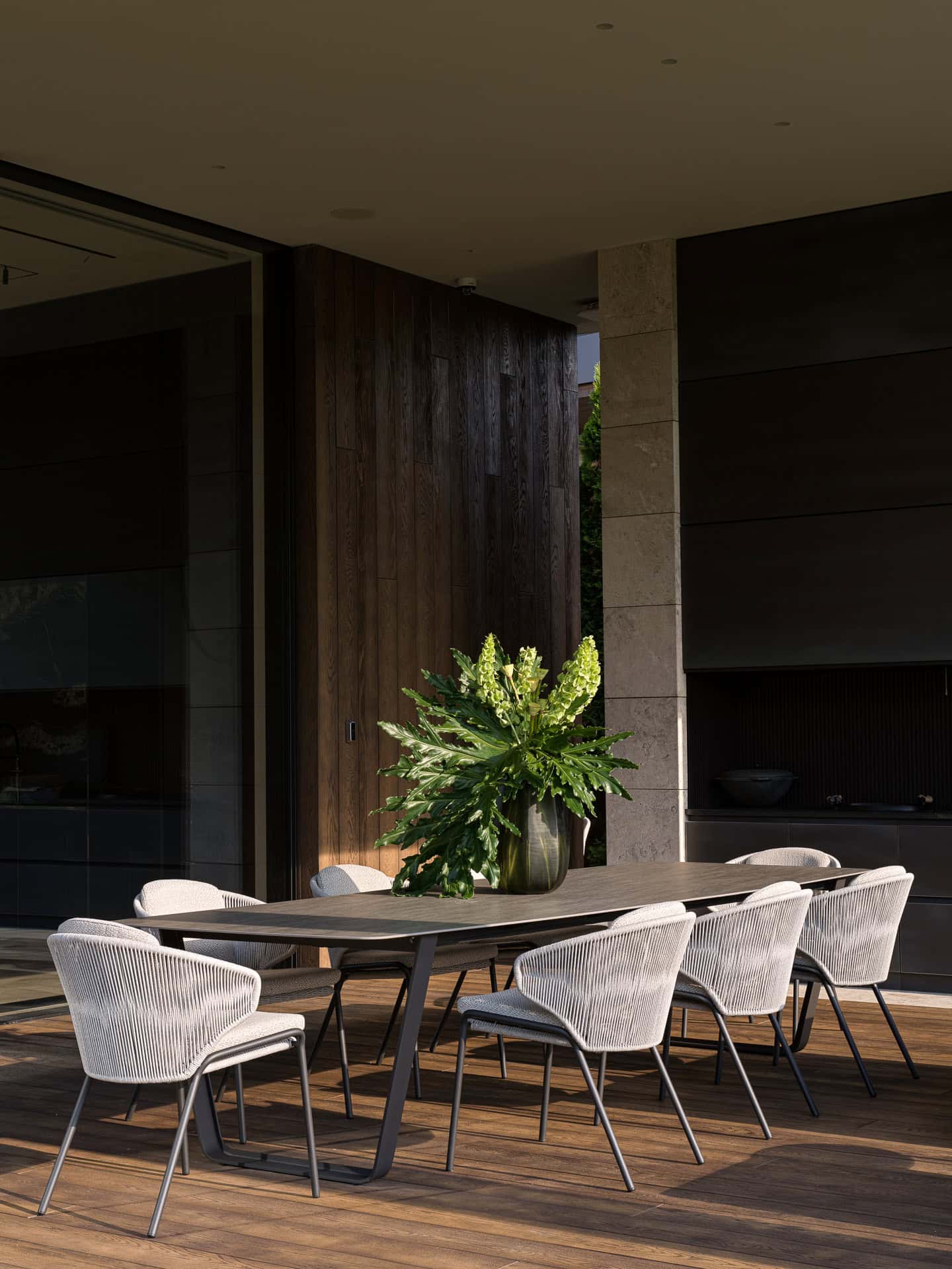 Outdoor Dining Set on Wooden Deck Outdoor dining area with modern chairs and flower arrangement on wooden deck.