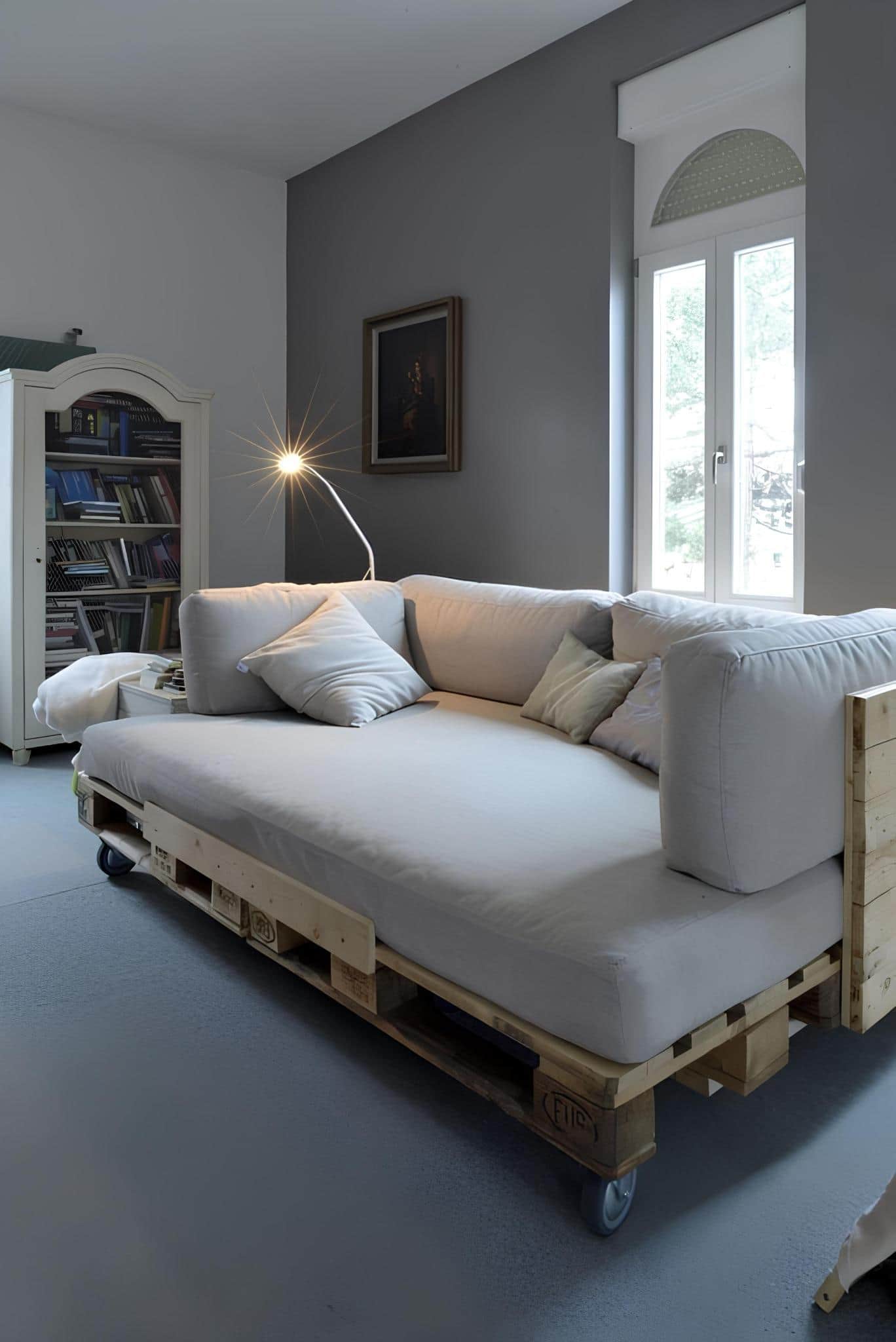 Stylish DIY daybed made from pallets with caster wheels and soft gray cushions