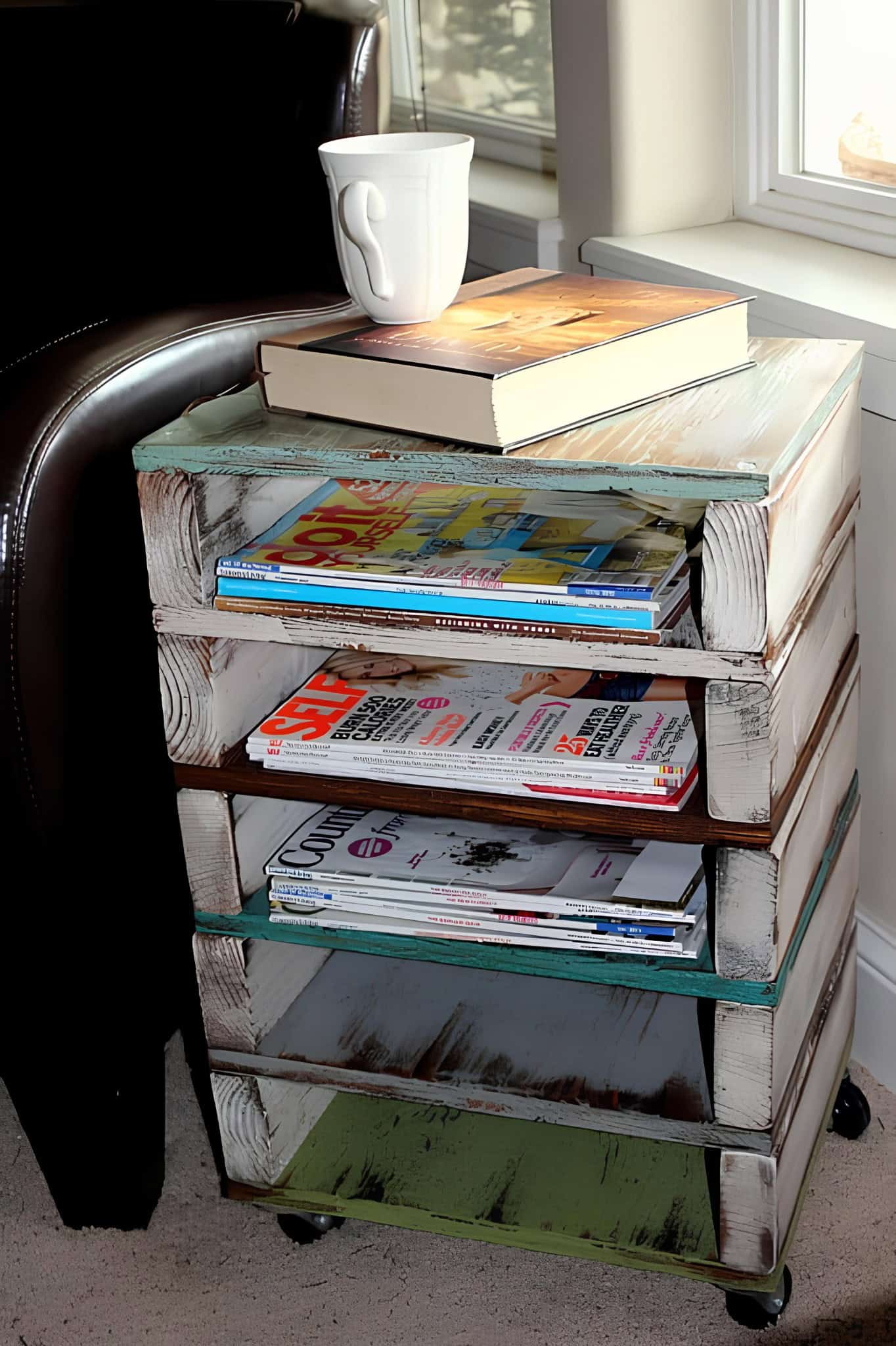 Compact side table made from pallets, featuring rustic paint and open shelving for books and magazines.