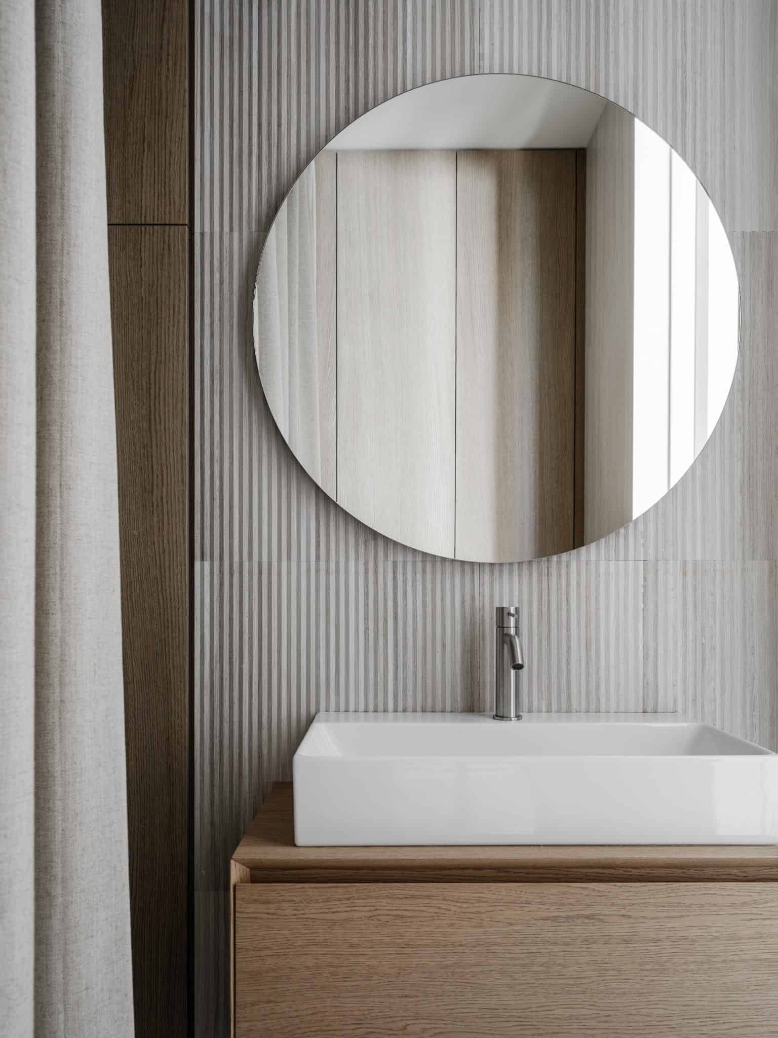 Round Mirror Above Wood Vanity In Bathroom Round mirror above wood vanity in bathroom.